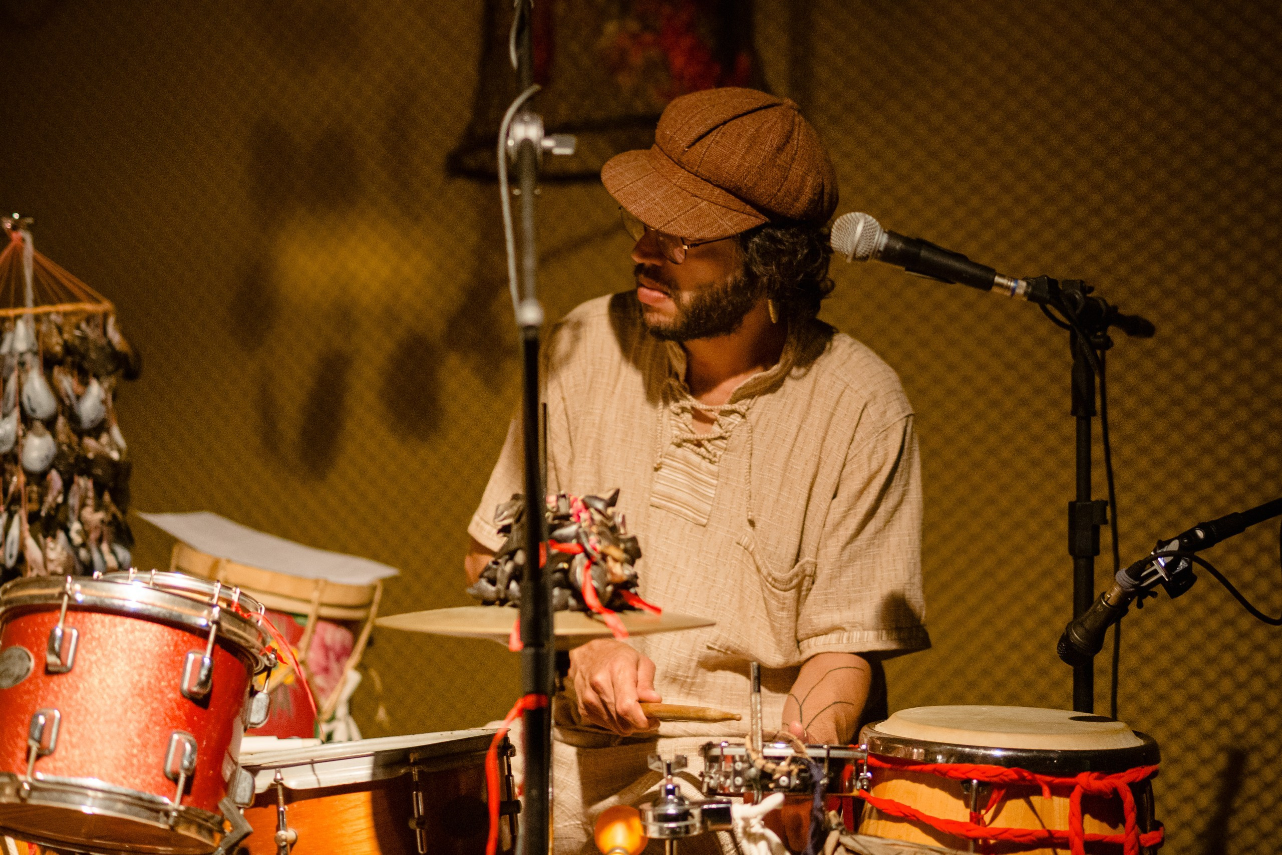 Fotógrafo de show em Balneário Camboriú; percussionista tocando bateria e instrumentos acústicos ao vivo no palco do bairro da Barra para a divulgação do projeto musical.
