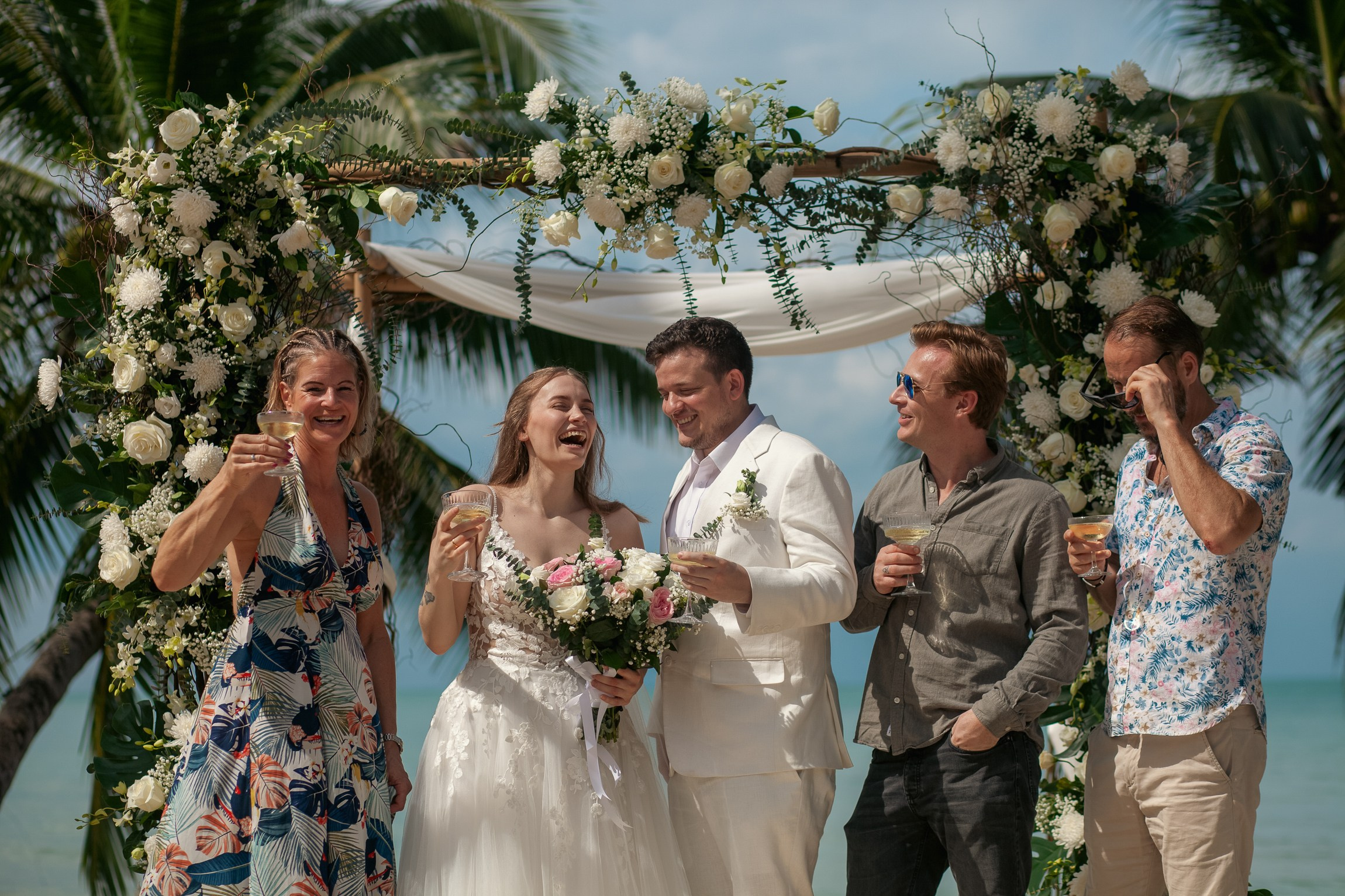 Romantic destination wedding on Koh Samui beach with tropical flowers, ocean views and happy newlyweds