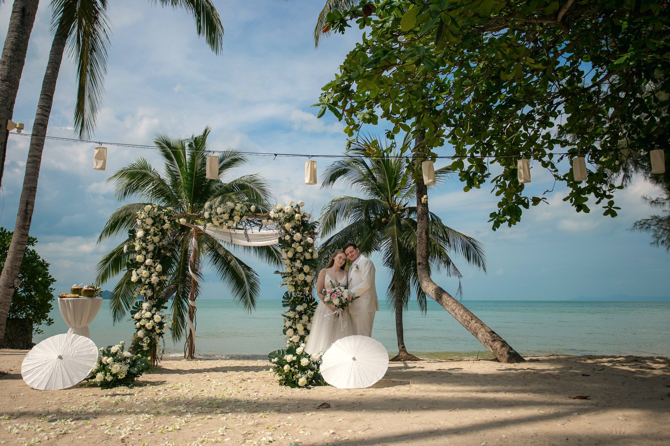 Romantic destination wedding on Koh Samui beach with tropical flowers, ocean views and happy newlyweds