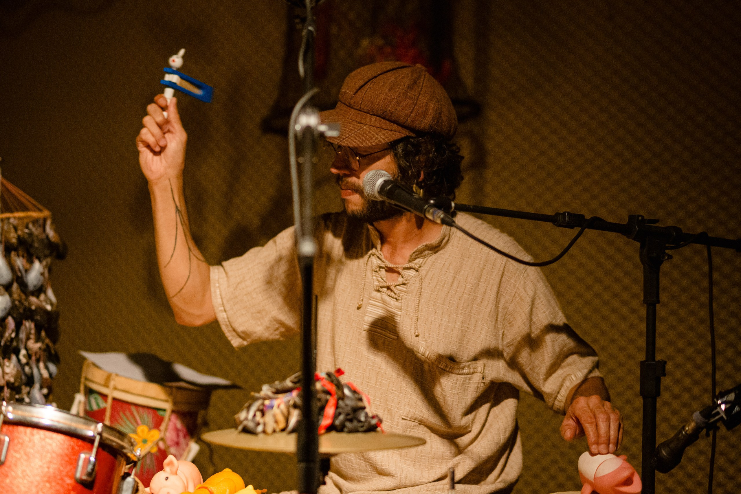 Fotógrafo de show em Balneário Camboriú; músico tocando percussão com chocalho e instrumentos criativos no palco durante apresentação no bairro da Barra para a divulgação do álbum "Água Brasileira".