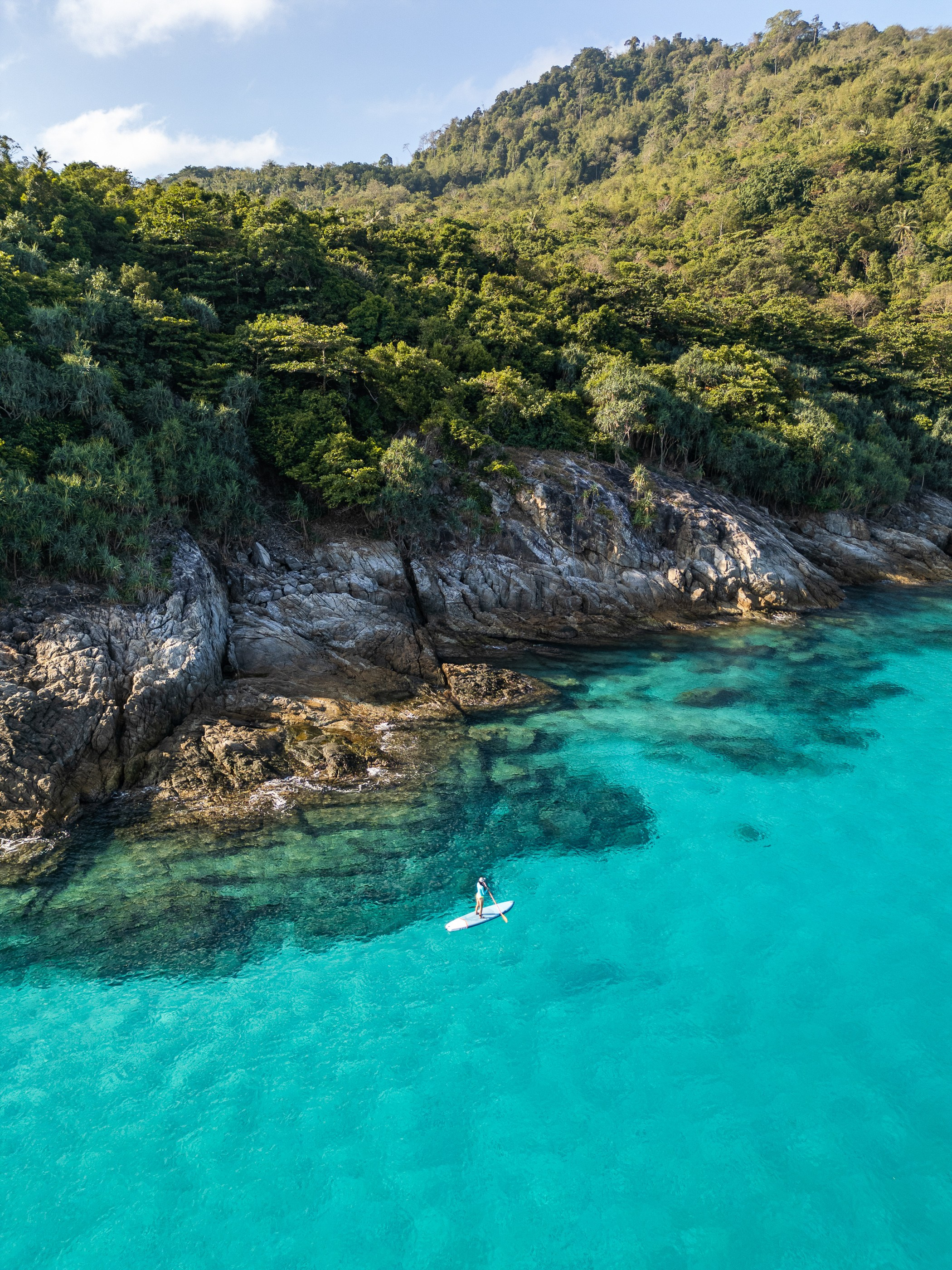 Woman paddleboarding along the dramatic coastline of the Andaman Sea, surrounded by towering limestone cliffs and tropical scenery, photographed for Destination Thailand social media promotion.