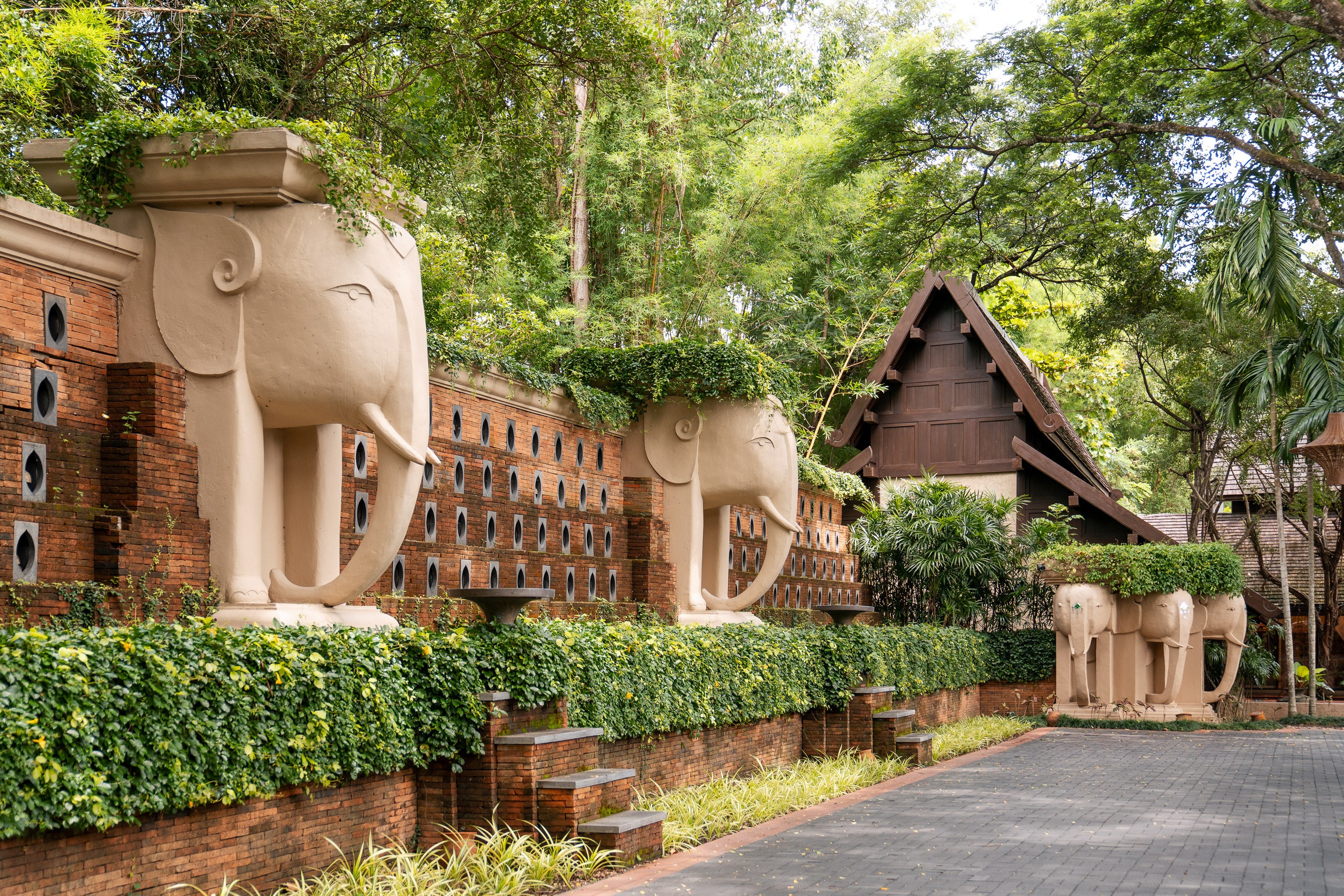 Distinctive hotel architecture with elephants along the entrance driveway leading towards the resort reception, blending luxury hospitality with tropical surroundings.