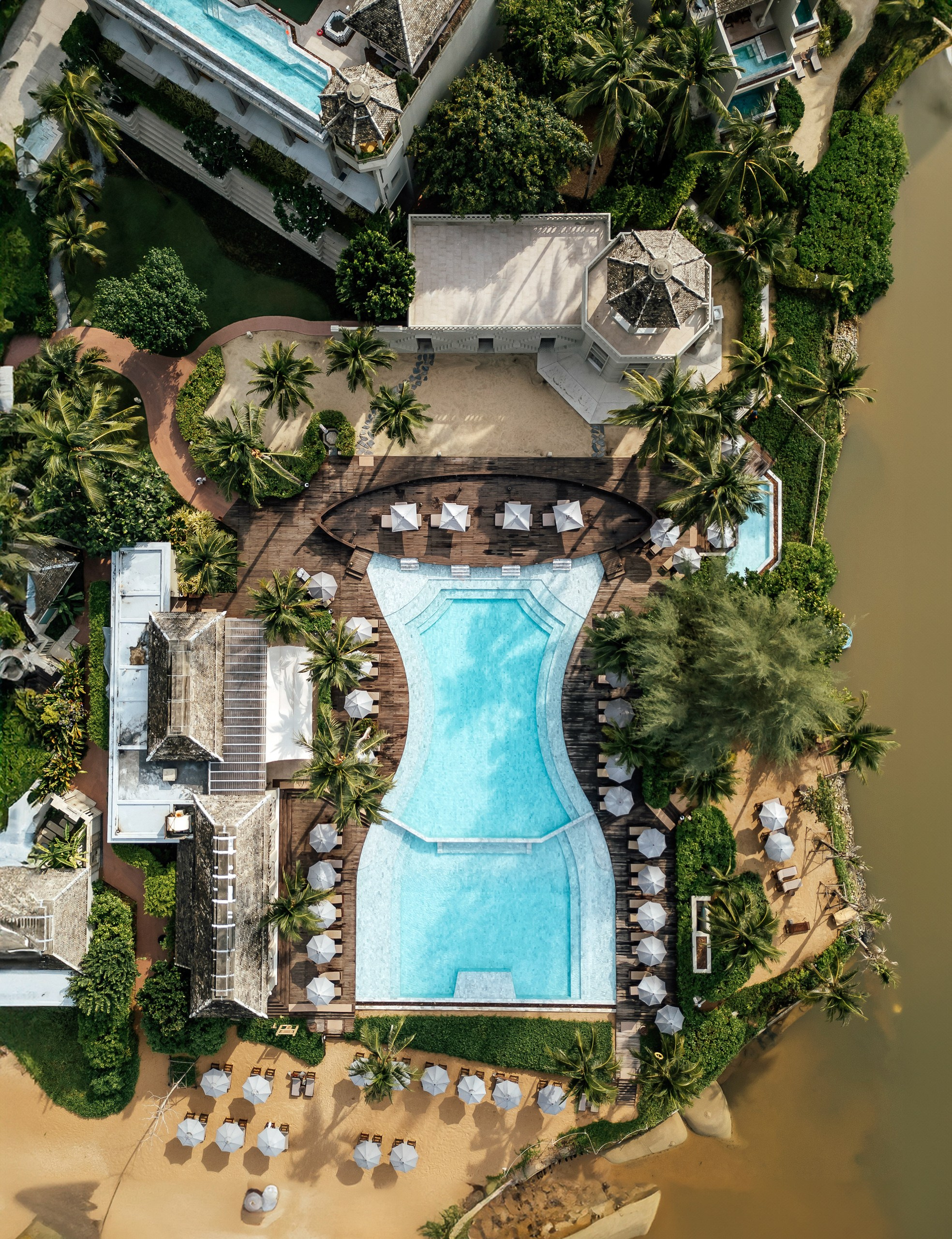 Aerial resort photography near Phuket featuring a tropical island coastline and crystal clear Andaman Sea