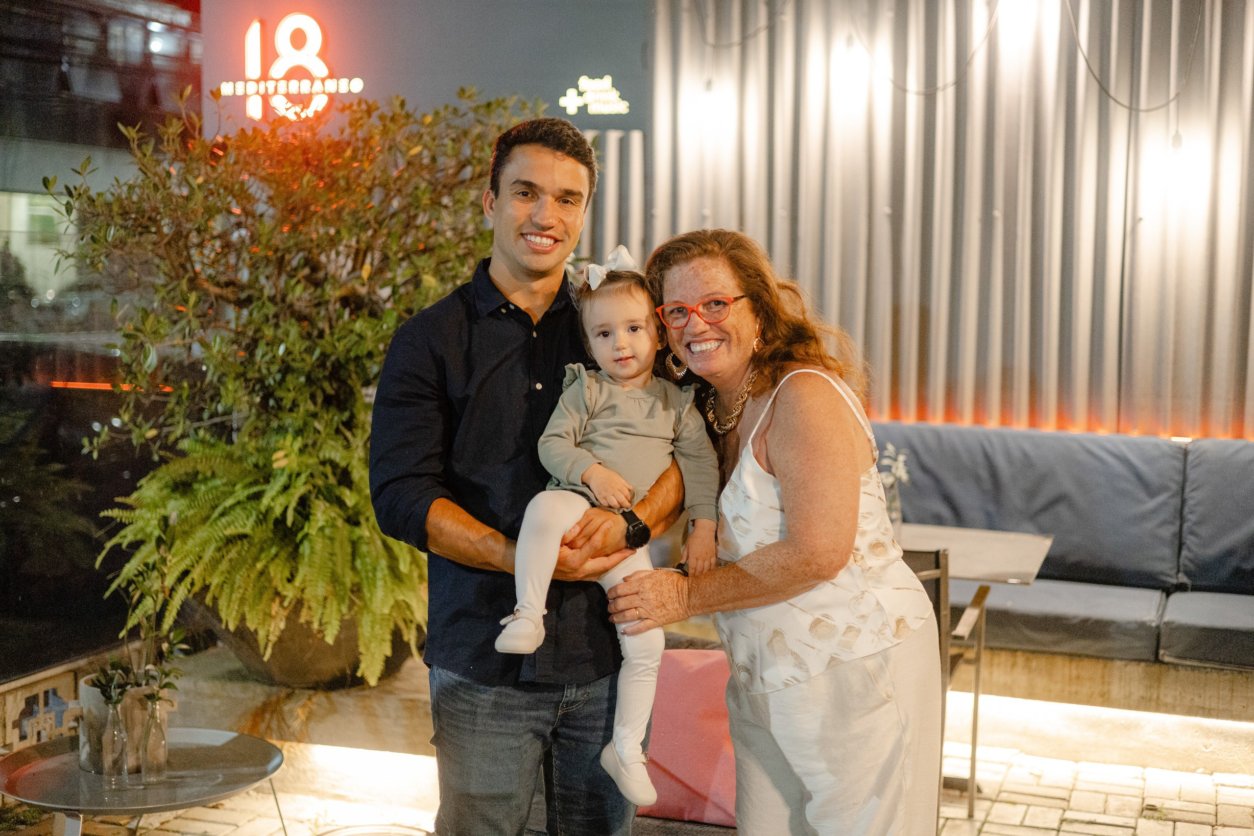 Fotógrafo de formatura em Balneário Camboriú; família sorridente posando no ambiente externo iluminado à noite.