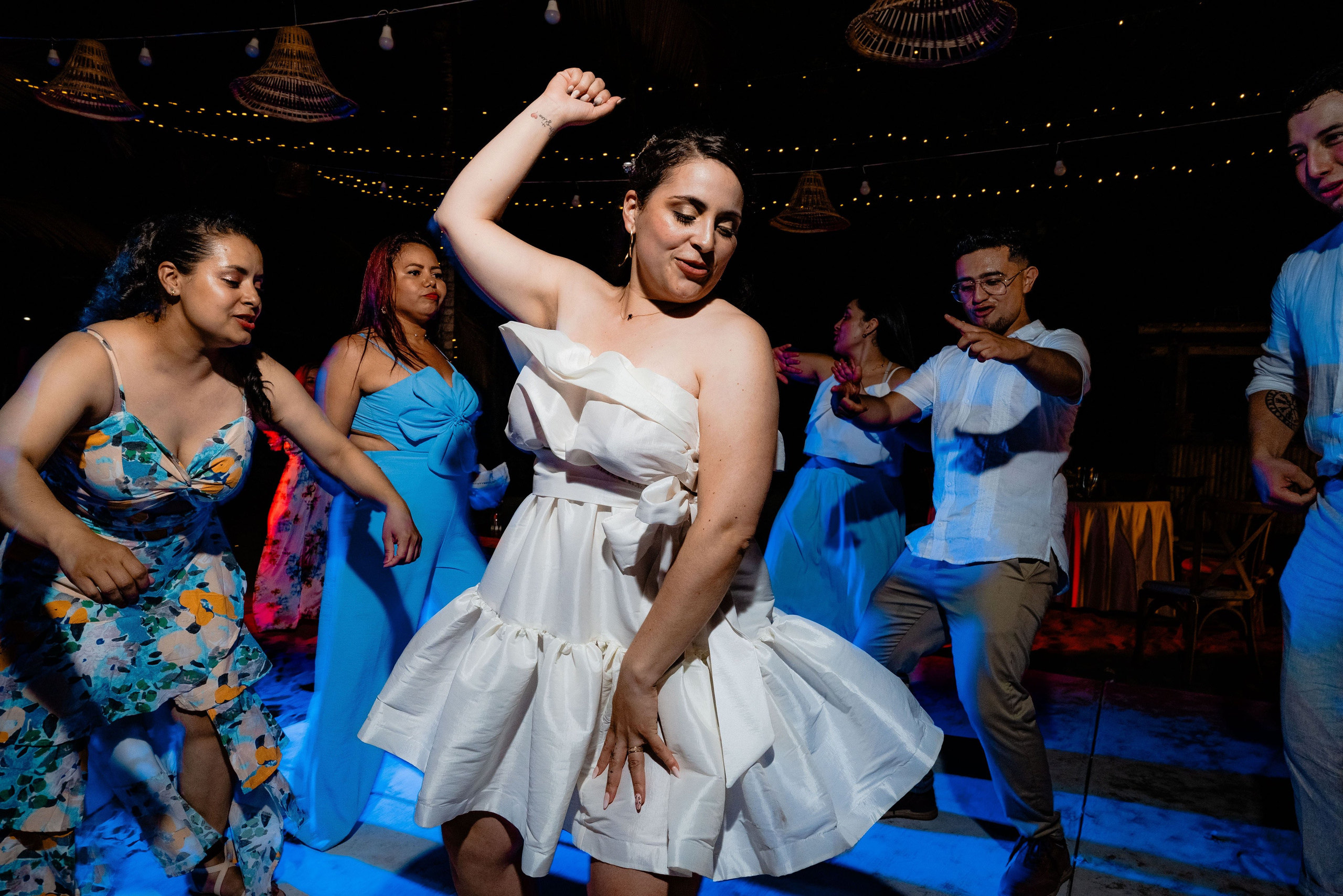 Novios y pareja disfrutando baile en fiesta de boda con iluminación azul tropical