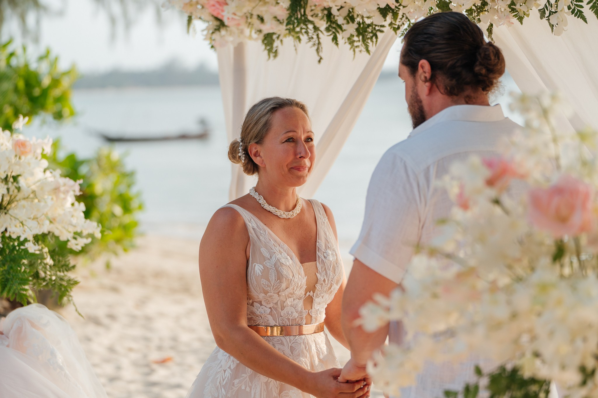 Bride and groom celebrating a beautiful beach wedding in Koh Samui, Thailand, surrounded by friends and family with tropical ocean views