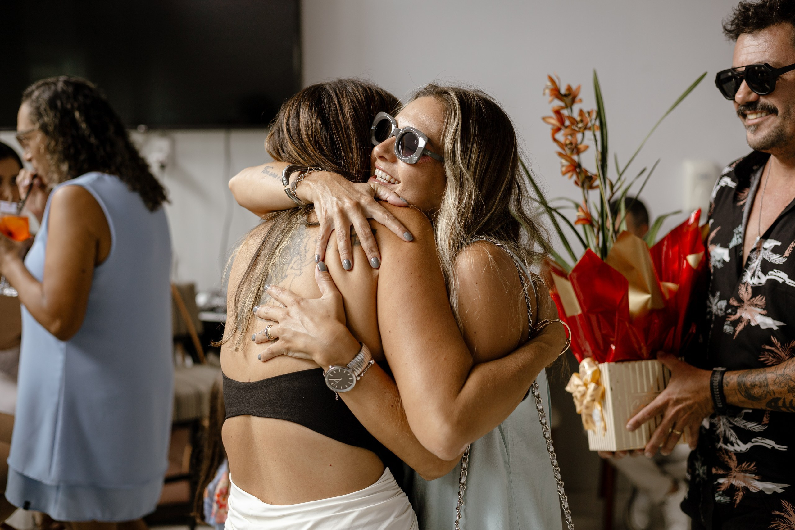 Fotografia de cobertura de festa e evento em Itajaí capturando o momento de abraço afetuoso e sorridente entre a aniversariante e uma convidada.