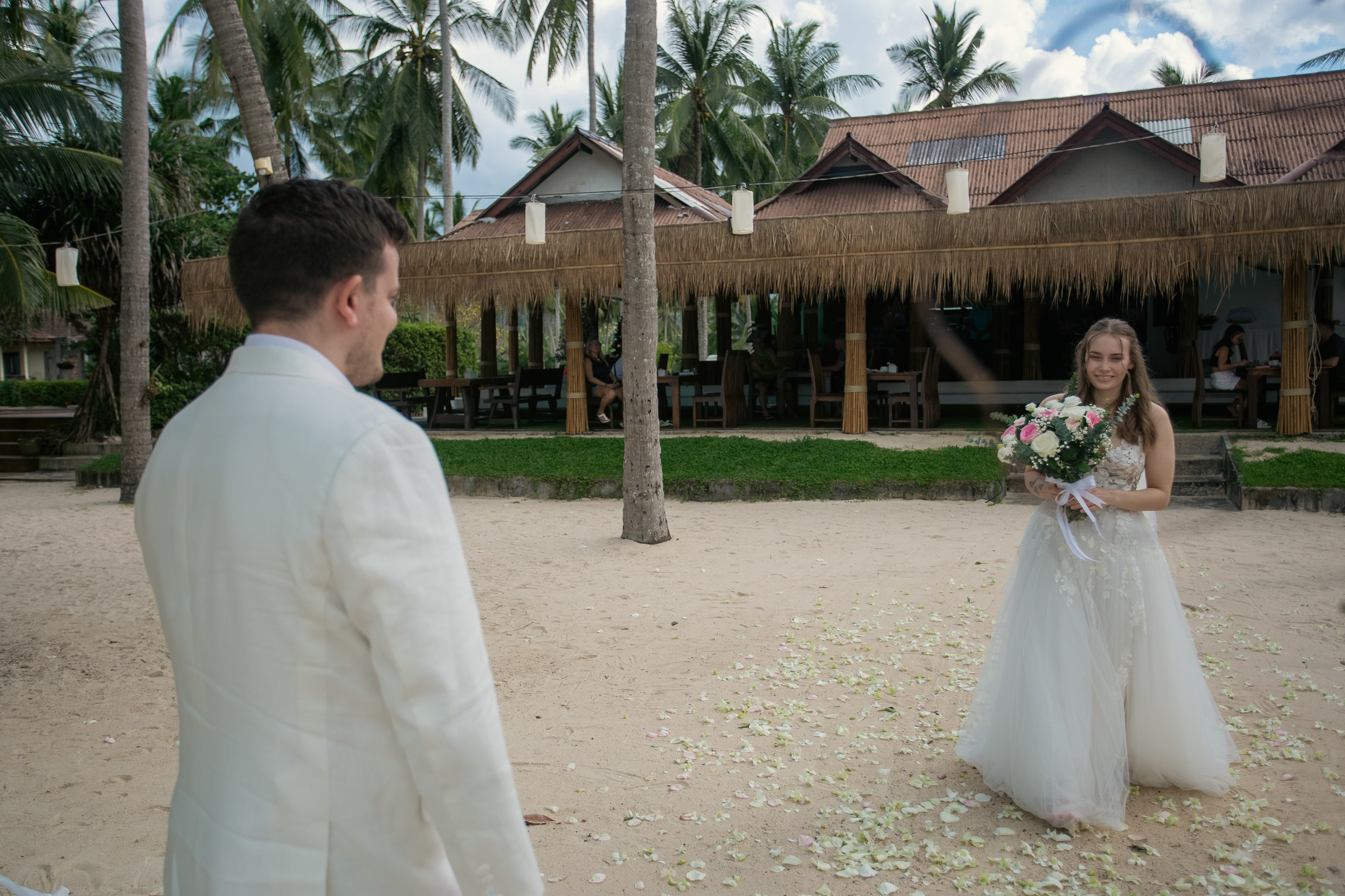 Bride and groom celebrating a beach wedding with their children in Koh Samui, Thailand, surrounded by tropical scenery and ocean views