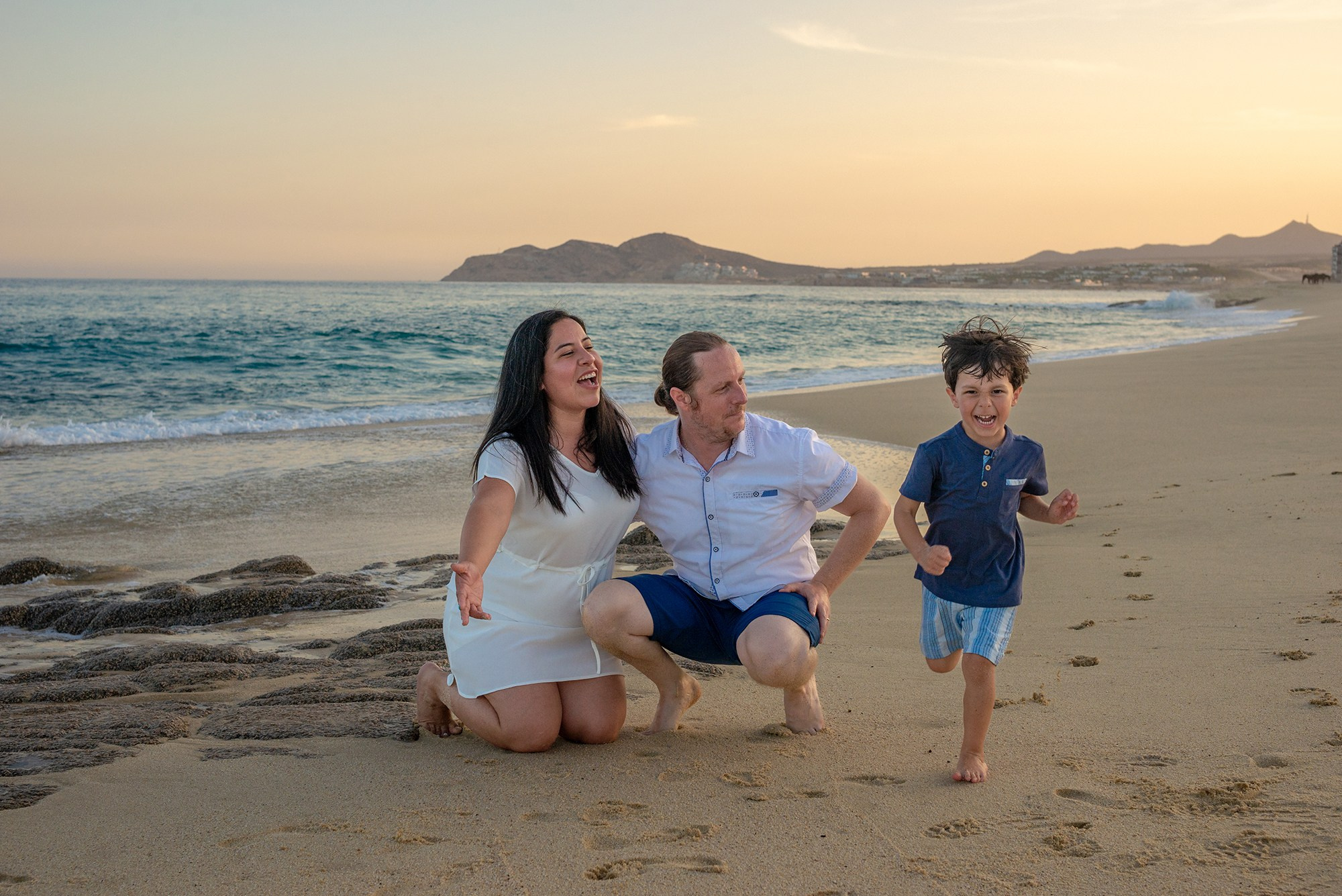 Family photoshoot in San Jose del Cabo – parents playing with their child at sunset on the beach at Villa La Valencia Resort