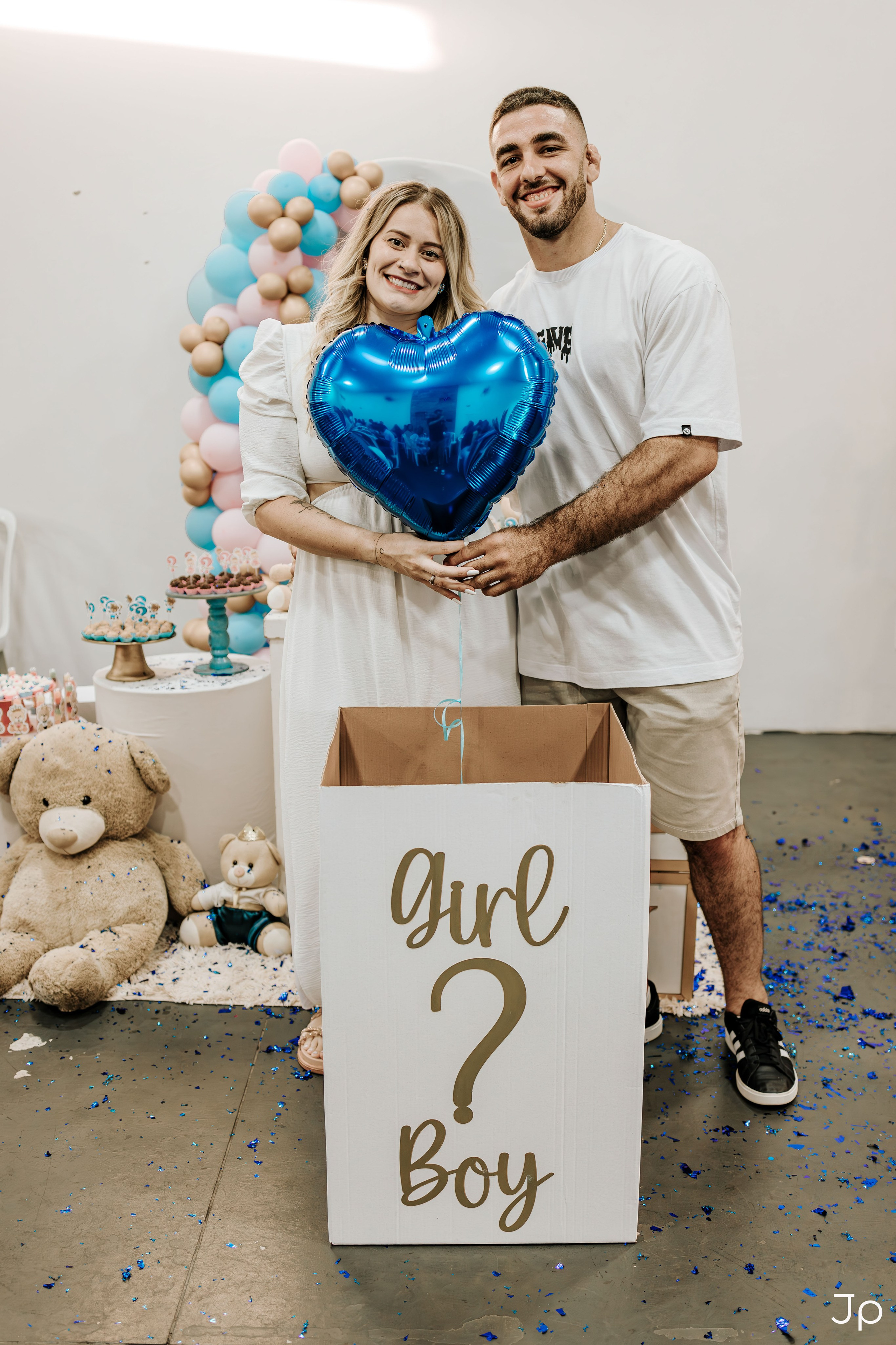 Casal segurando bexiga azul metálica em ensaio de gestante.
