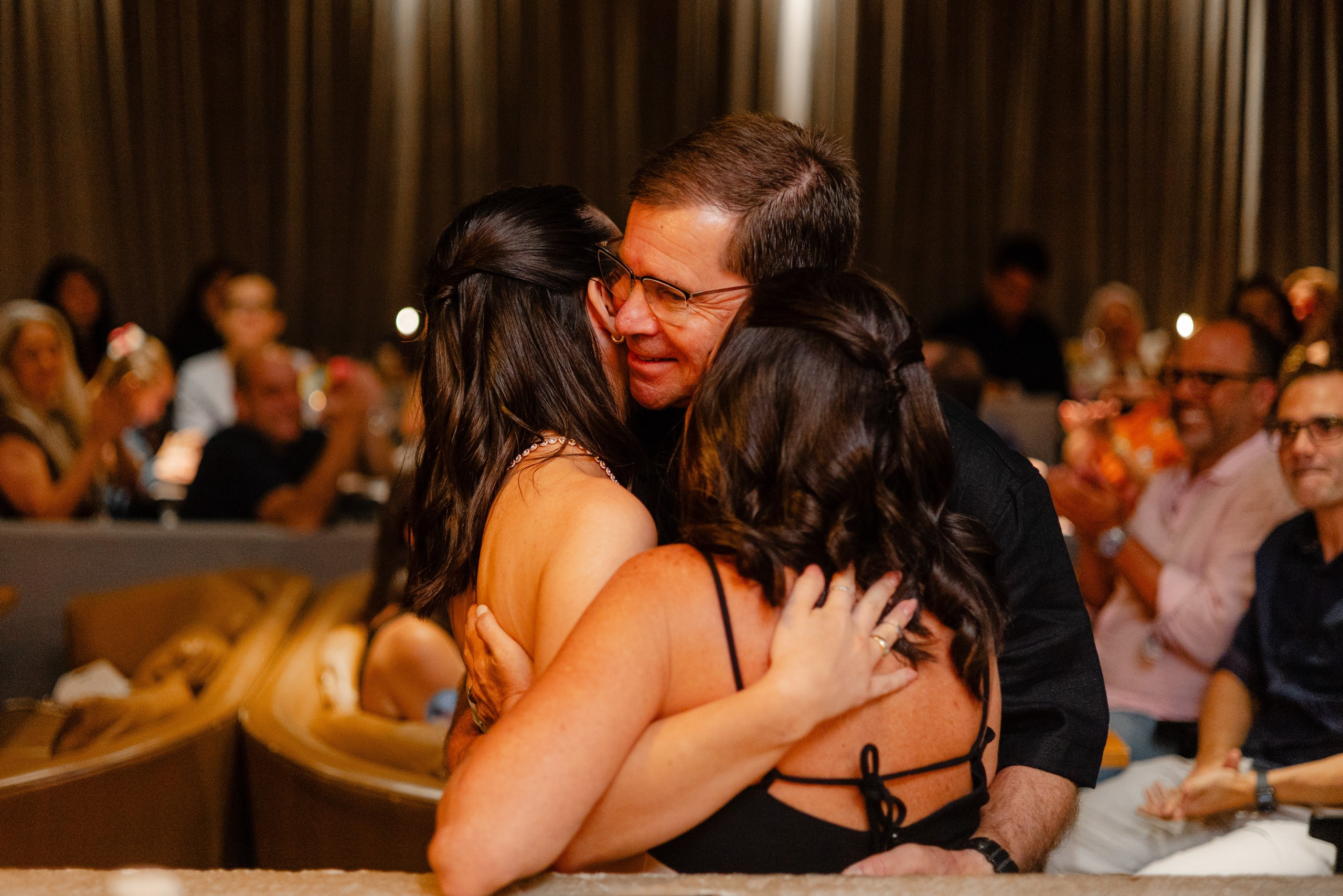 Fotógrafo de festa de formatura em Balneário Camboriú; formanda abraçando os pais após discurso.