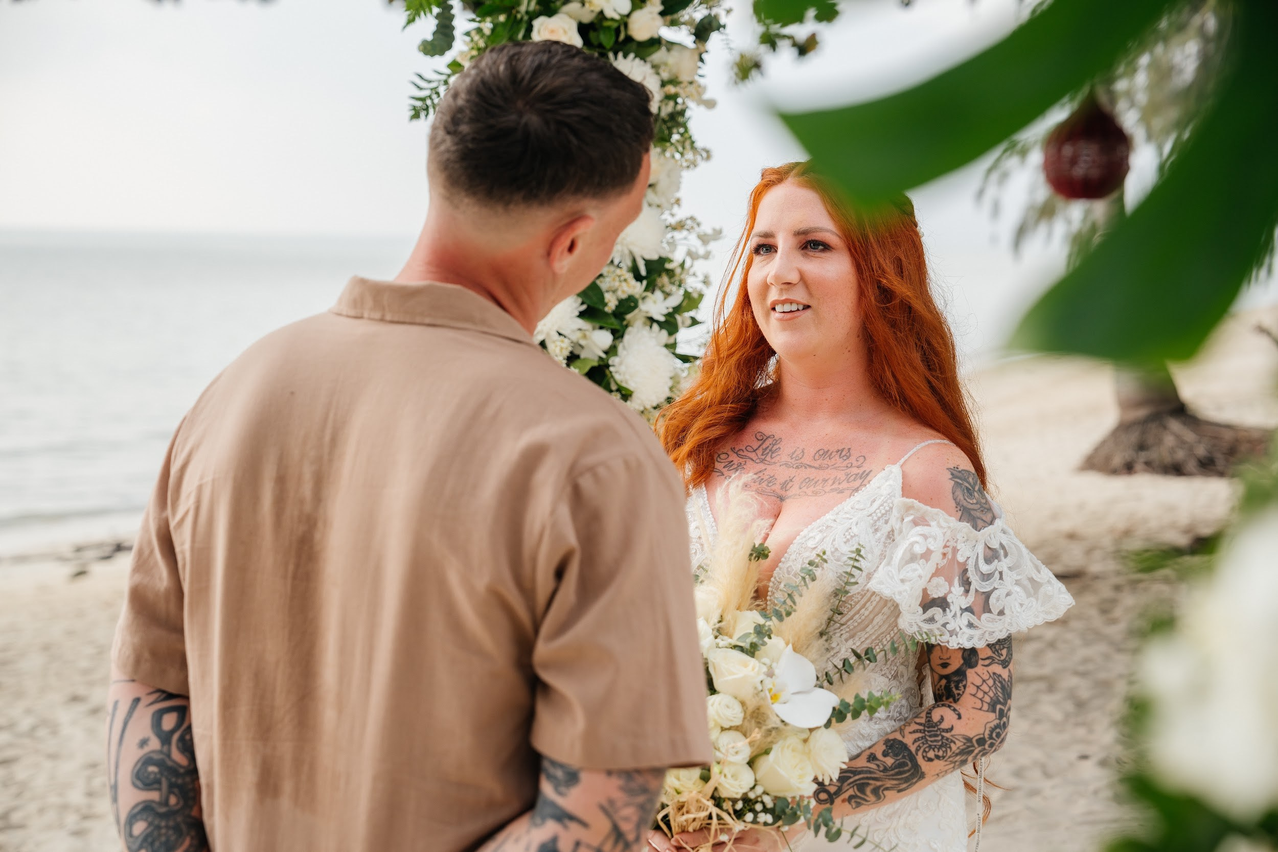 Wedding ceremony on a tropical beach in Koh Samui, Thailand with floral arch and turquoise sea in the background