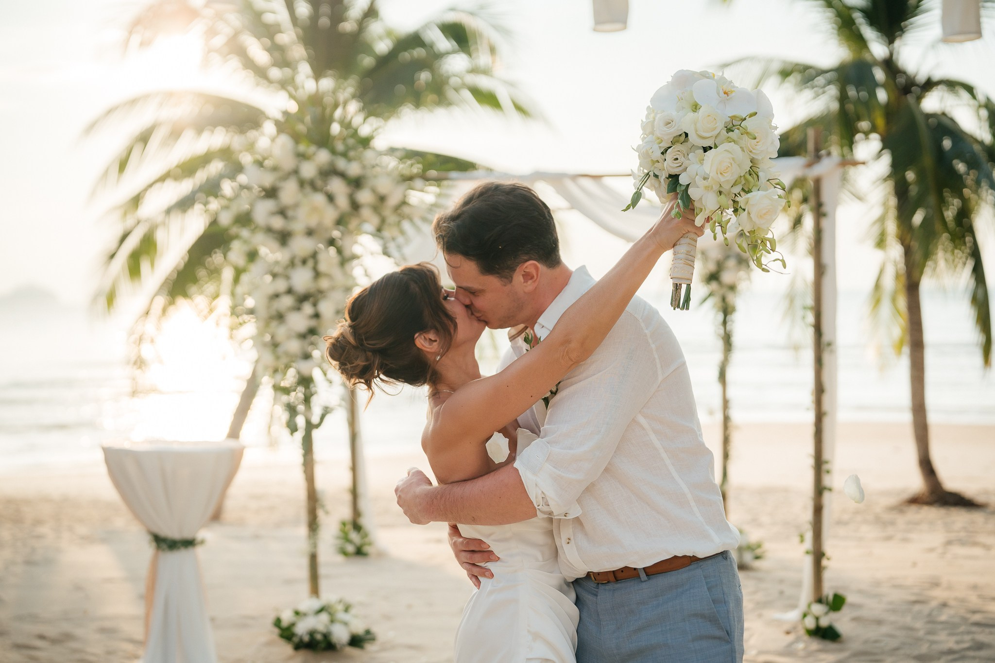 Bride and groom celebrating a beach wedding with their children in Koh Samui, Thailand, surrounded by tropical scenery and ocean views