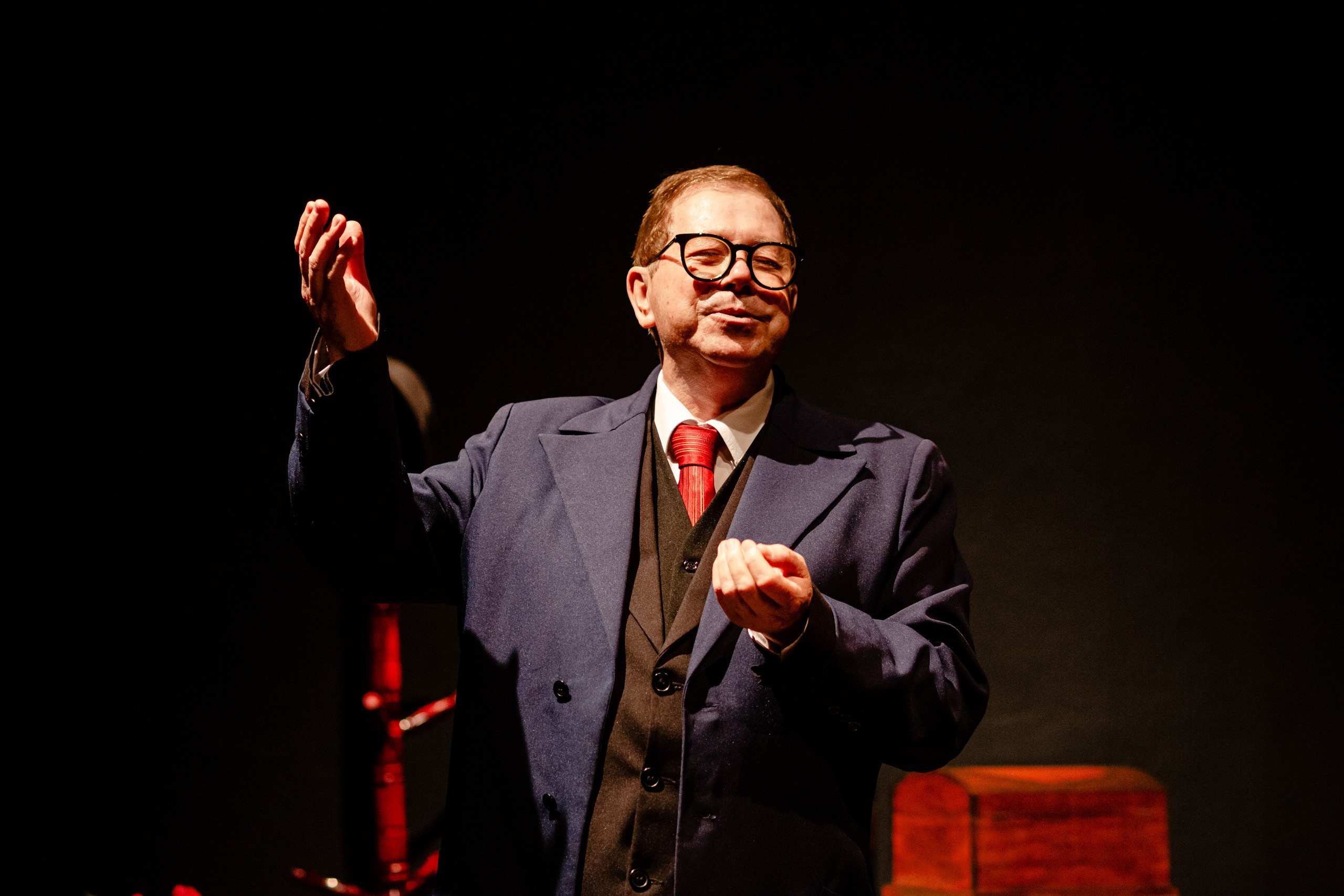 Apresentação teatral com ator fazendo encenação no palco.