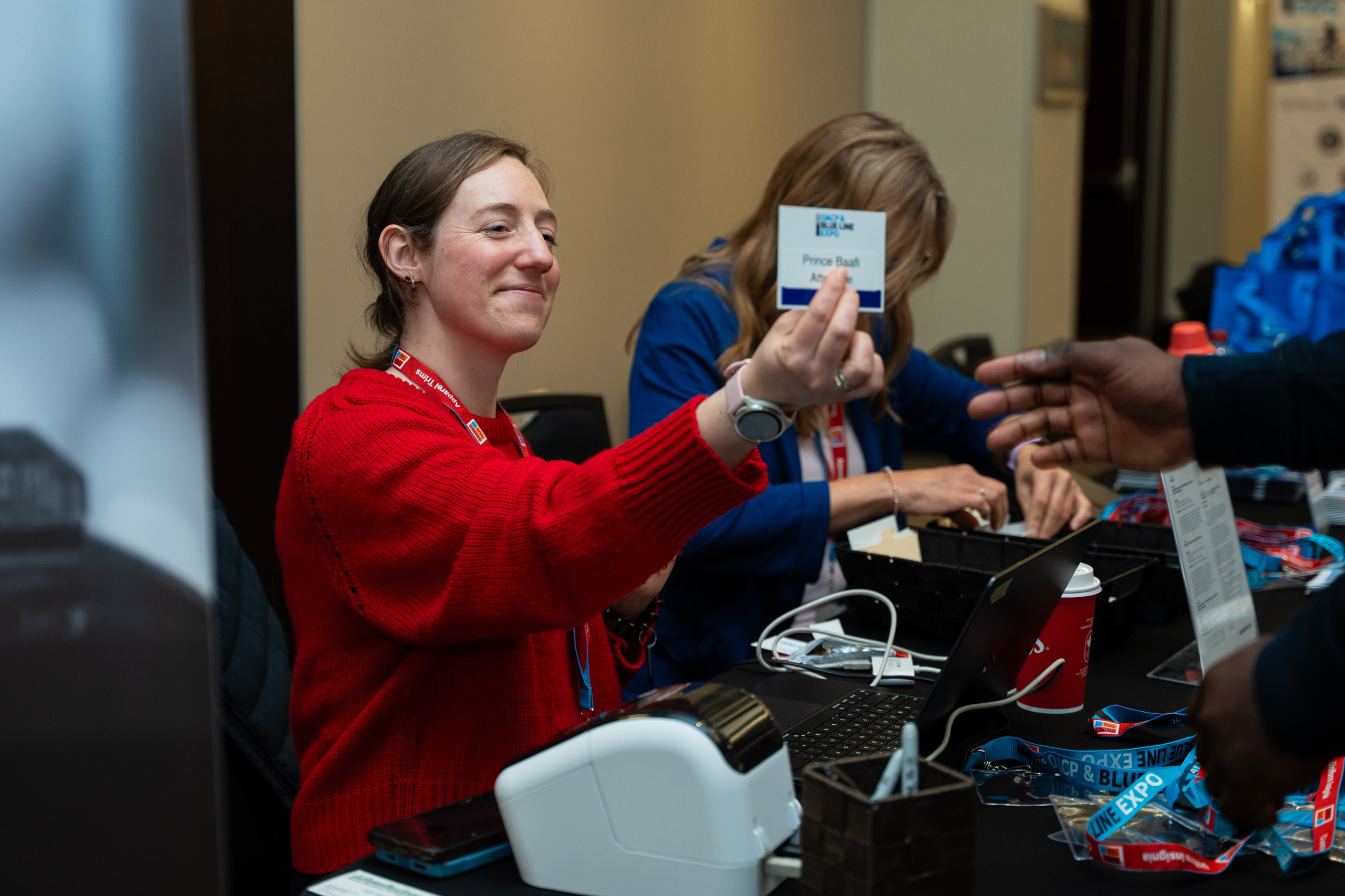 Attendee reaching for item at exhibitor booth, Blueline Expo
