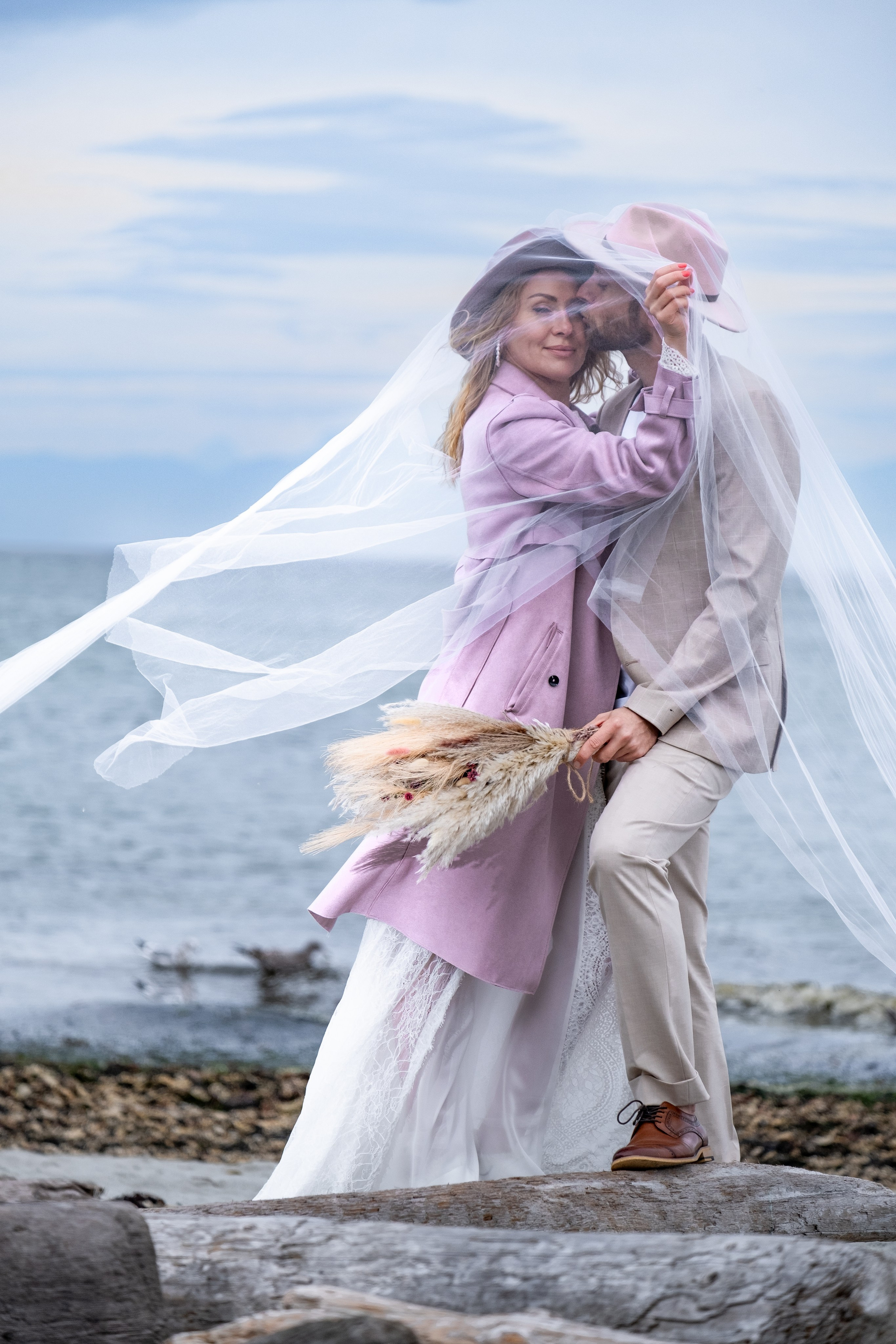 cinematic wedding couple standing near ocean waves