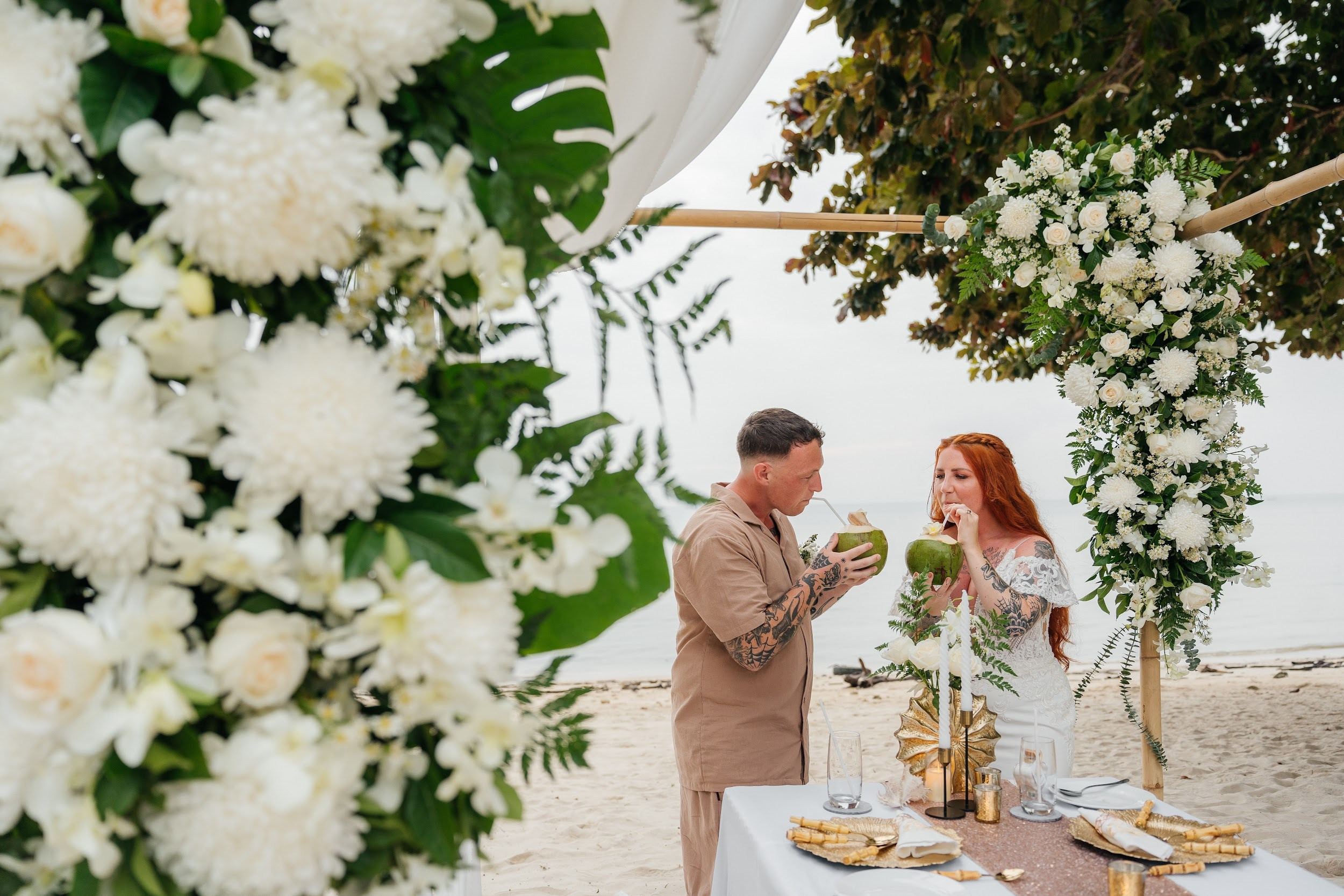 Wedding ceremony on a tropical beach in Koh Samui, Thailand with floral arch and turquoise sea in the background