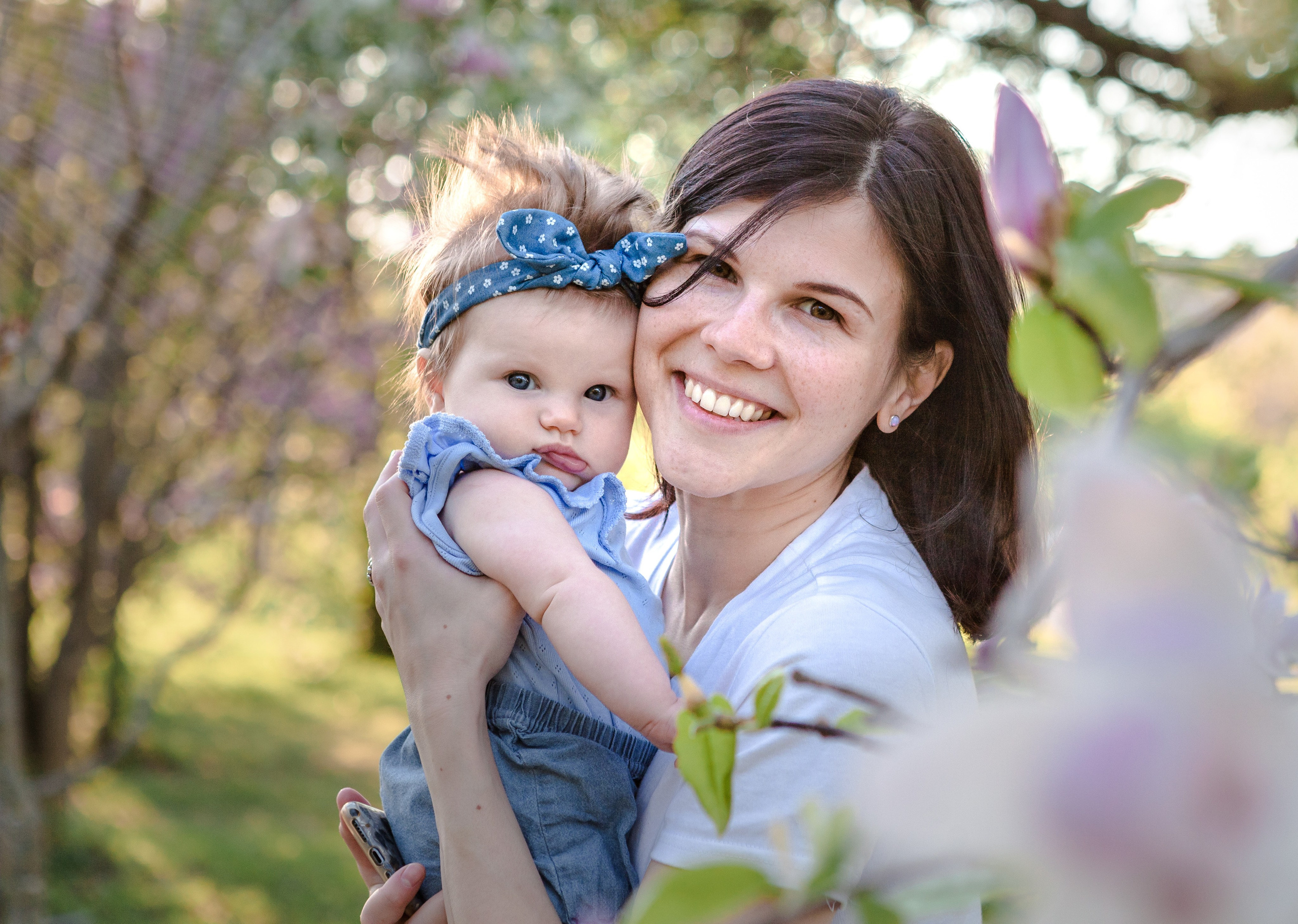 Spring family portrait with blooming magnolia trees, artistic natural lighting, at Central Experimental Farm near Dow's Lake in Ottawa.