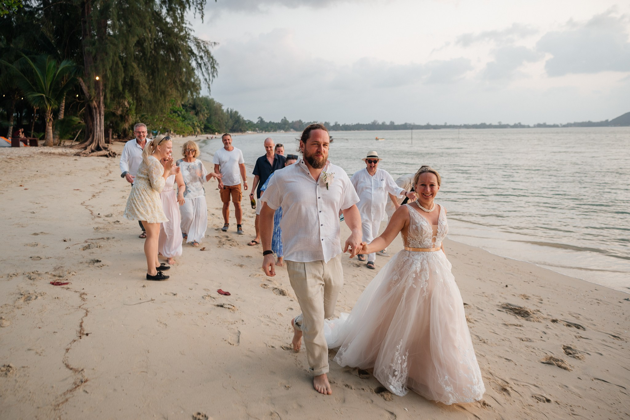 Bride and groom celebrating a beautiful beach wedding in Koh Samui, Thailand, surrounded by friends and family with tropical ocean views
