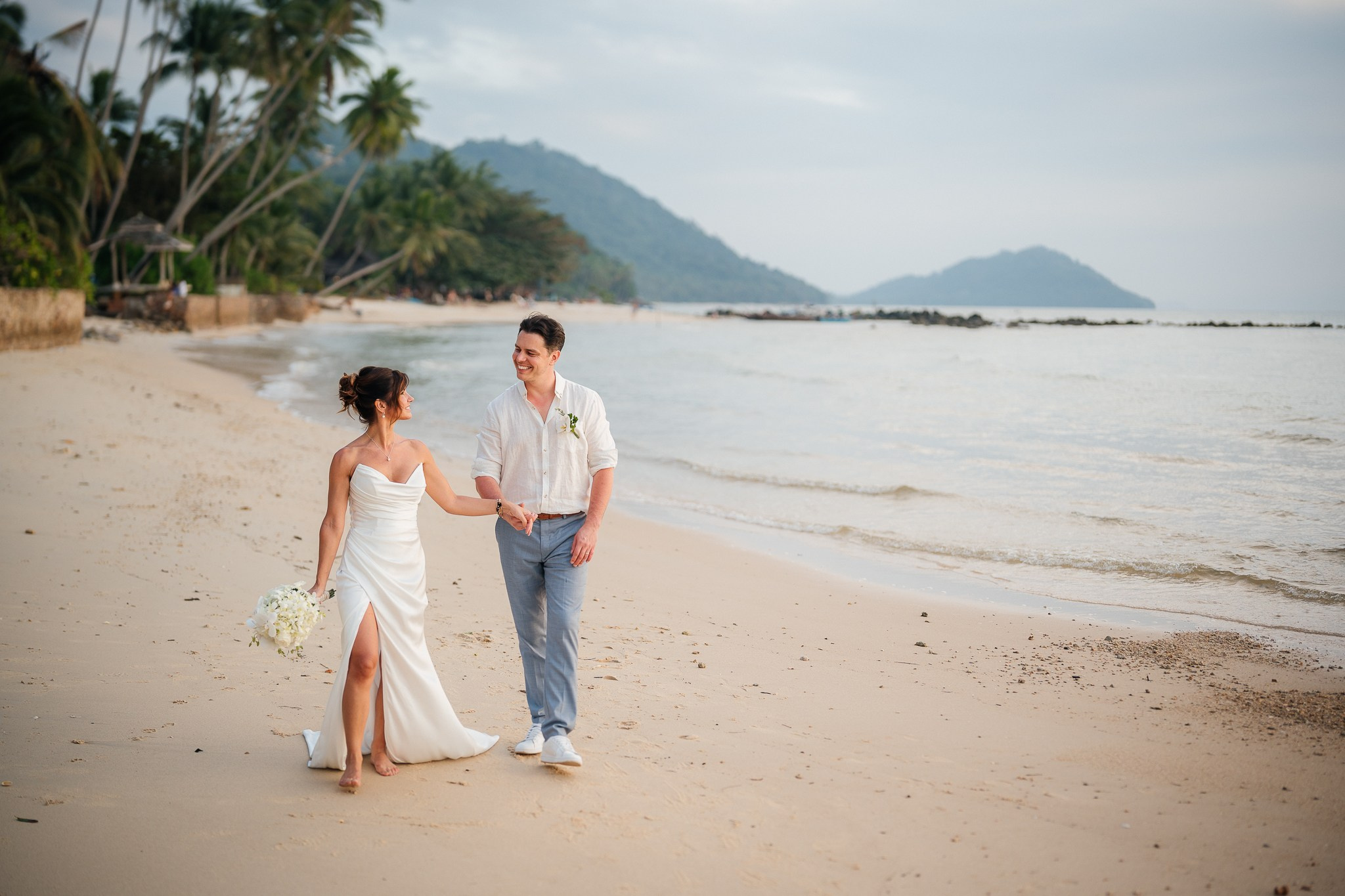 Bride and groom celebrating a beach wedding with their children in Koh Samui, Thailand, surrounded by tropical scenery and ocean views
