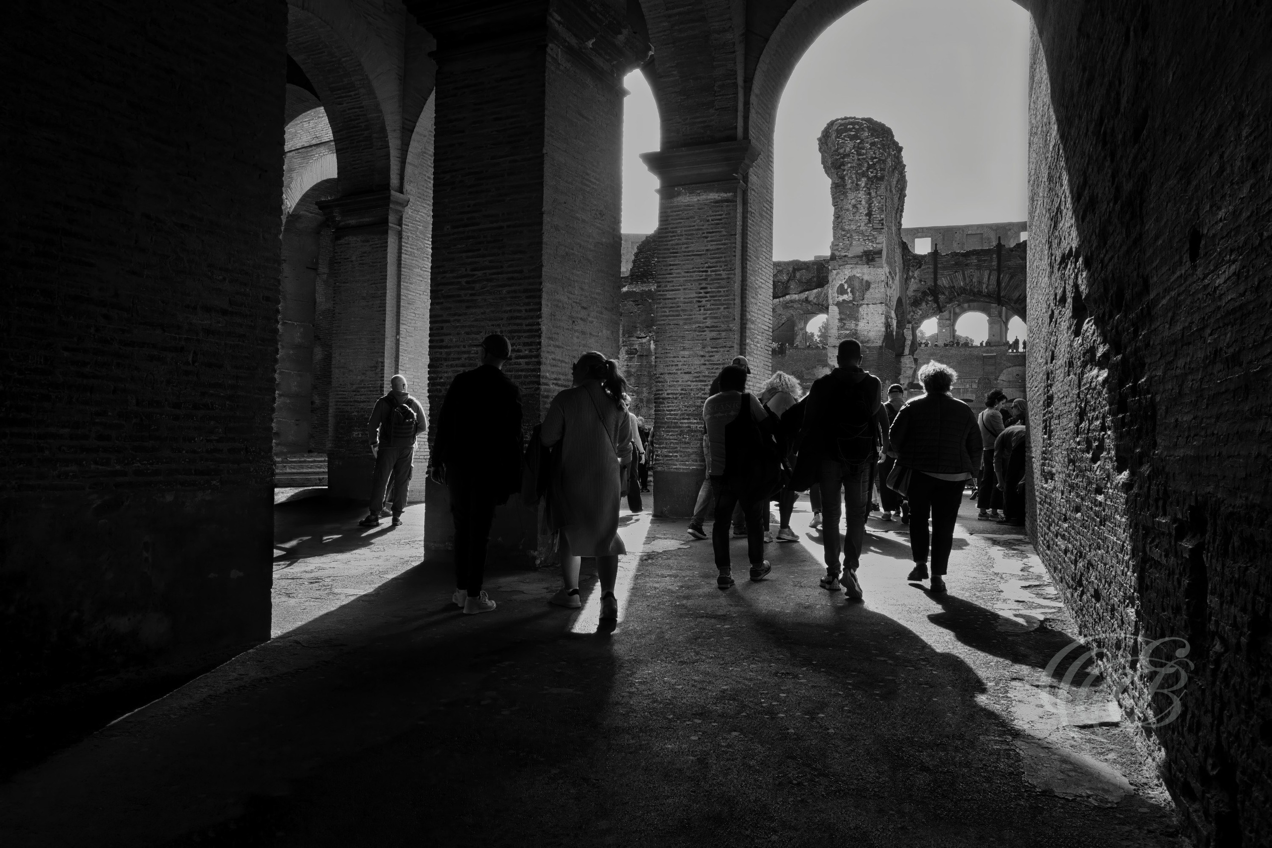 Rome, Italy — The Colosseum Archways — Eduardo Bartoli Photography — Black and white photograph from within the Colosseum, showing ancient archways opening toward the arena with silhouetted visitors, dramatic light, and historic Roman architecture in Rome, Italy — Eduardo Bartoli Photography.