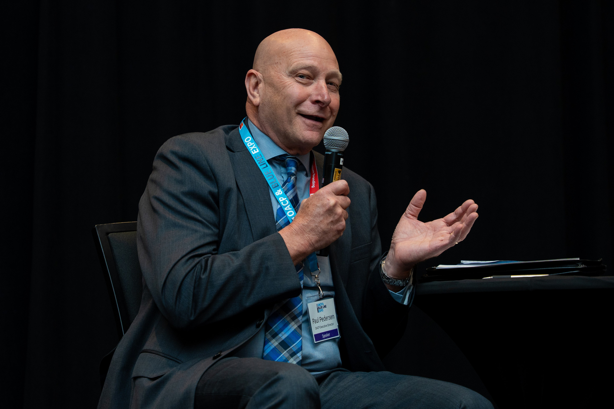 Speaker in chair gesturing during discussion, Blueline Expo