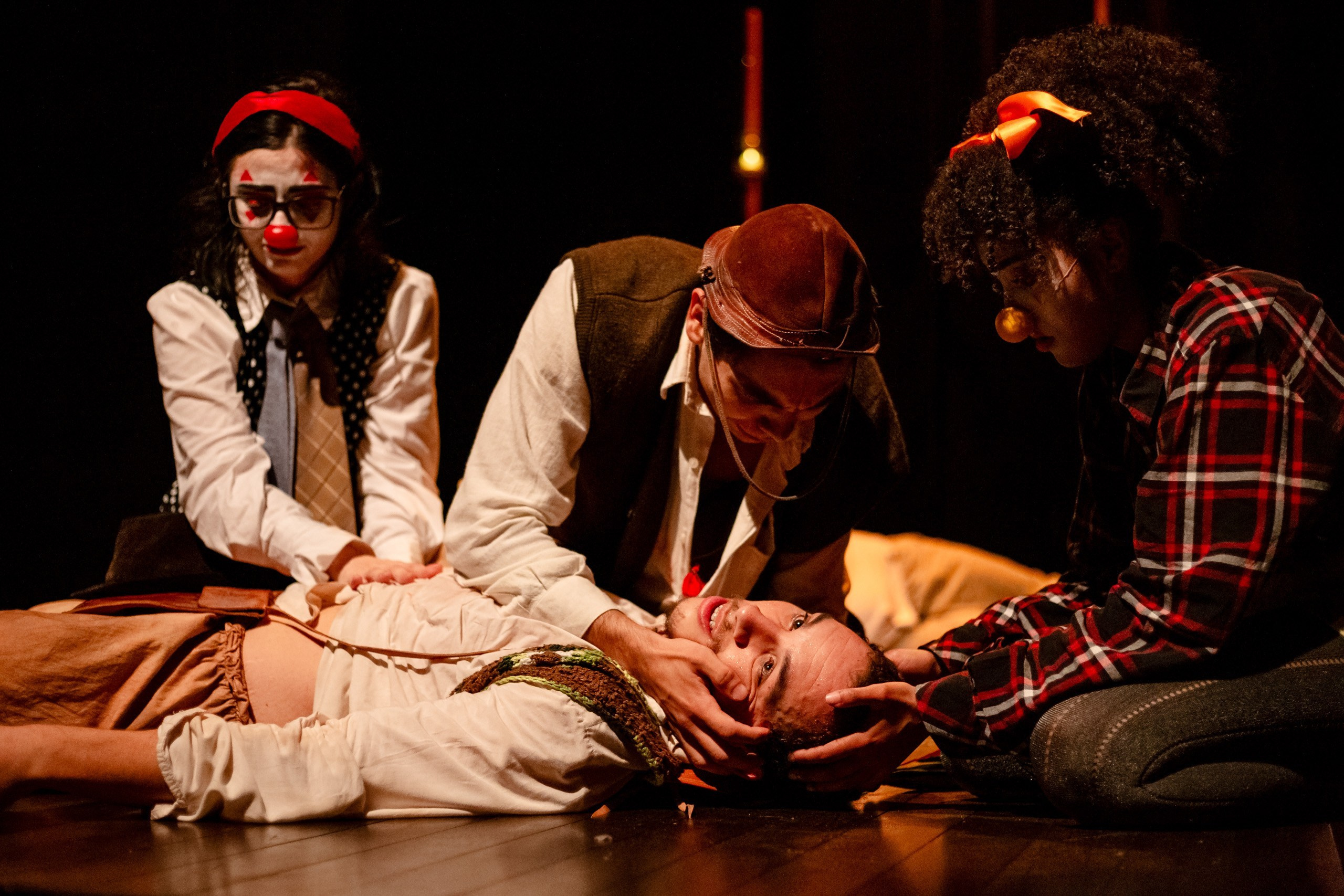 Apresentação teatral com ator segurando a cabeça de outro.