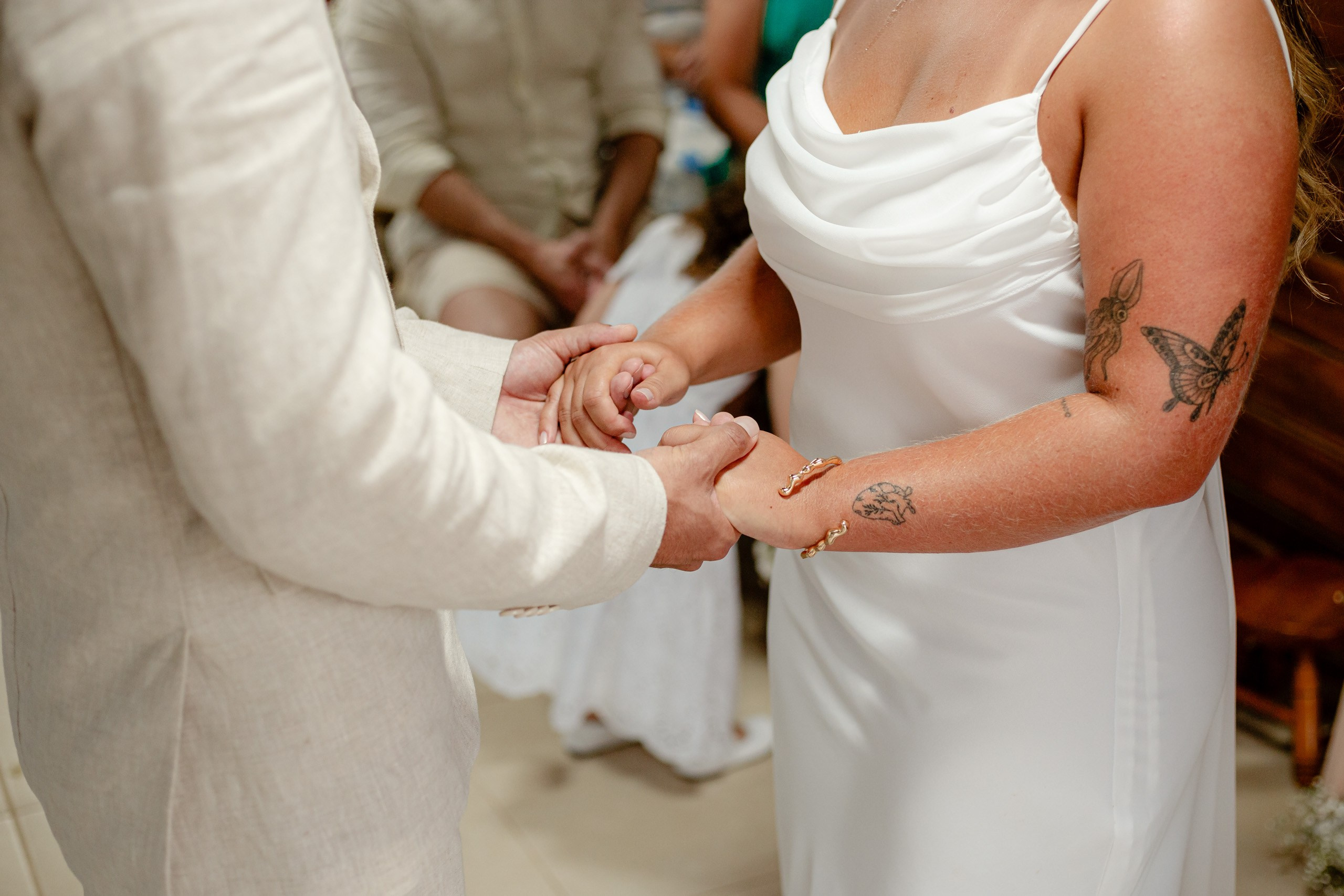 Fotógrafo de casamento em Bombinhas; close detalhe do noivo e da noiva de mãos dadas durante os votos no altar.
