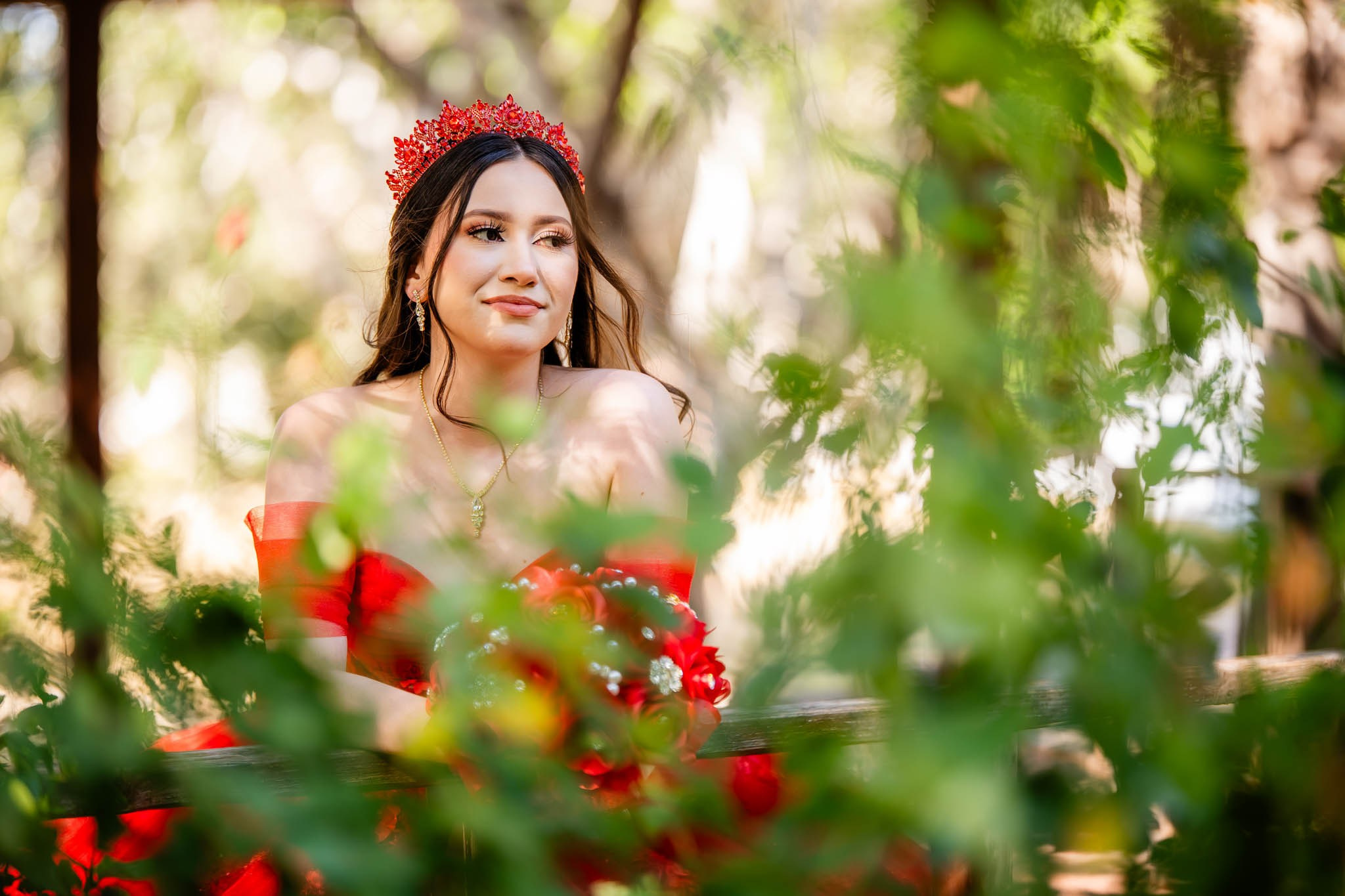 Quinceanera entre hojas y flores en Parque Hacienda Aguacaliente Tijuana vestido rojo fotografia natural en exterior