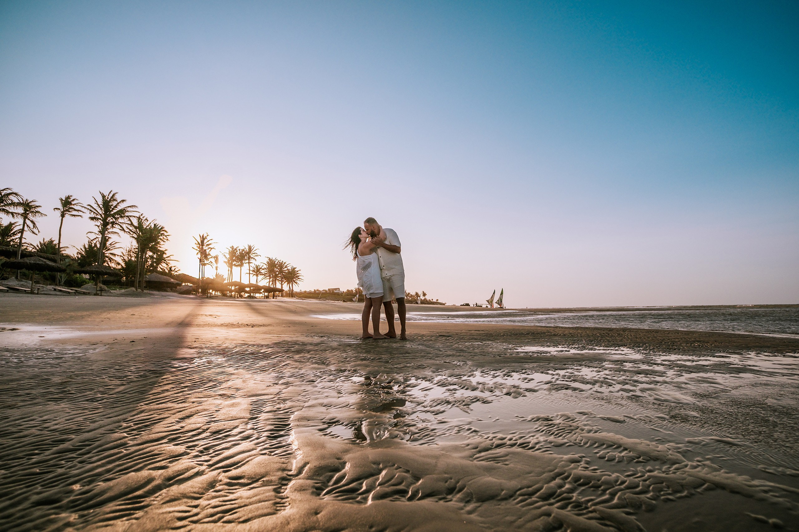casal abraçado na praia enquanto mostra paisagem