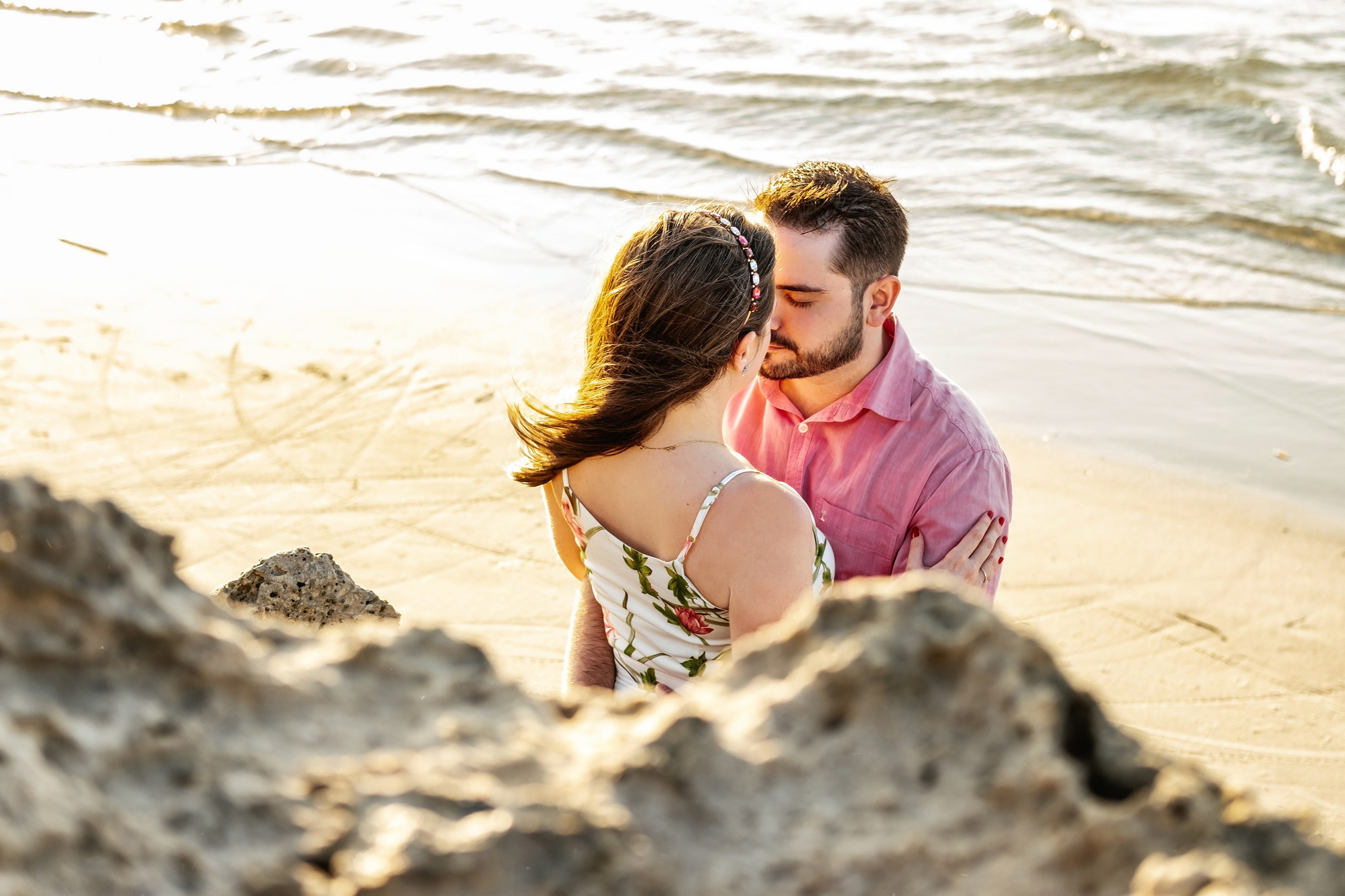 Casal abraçado encostados em pedras na praia