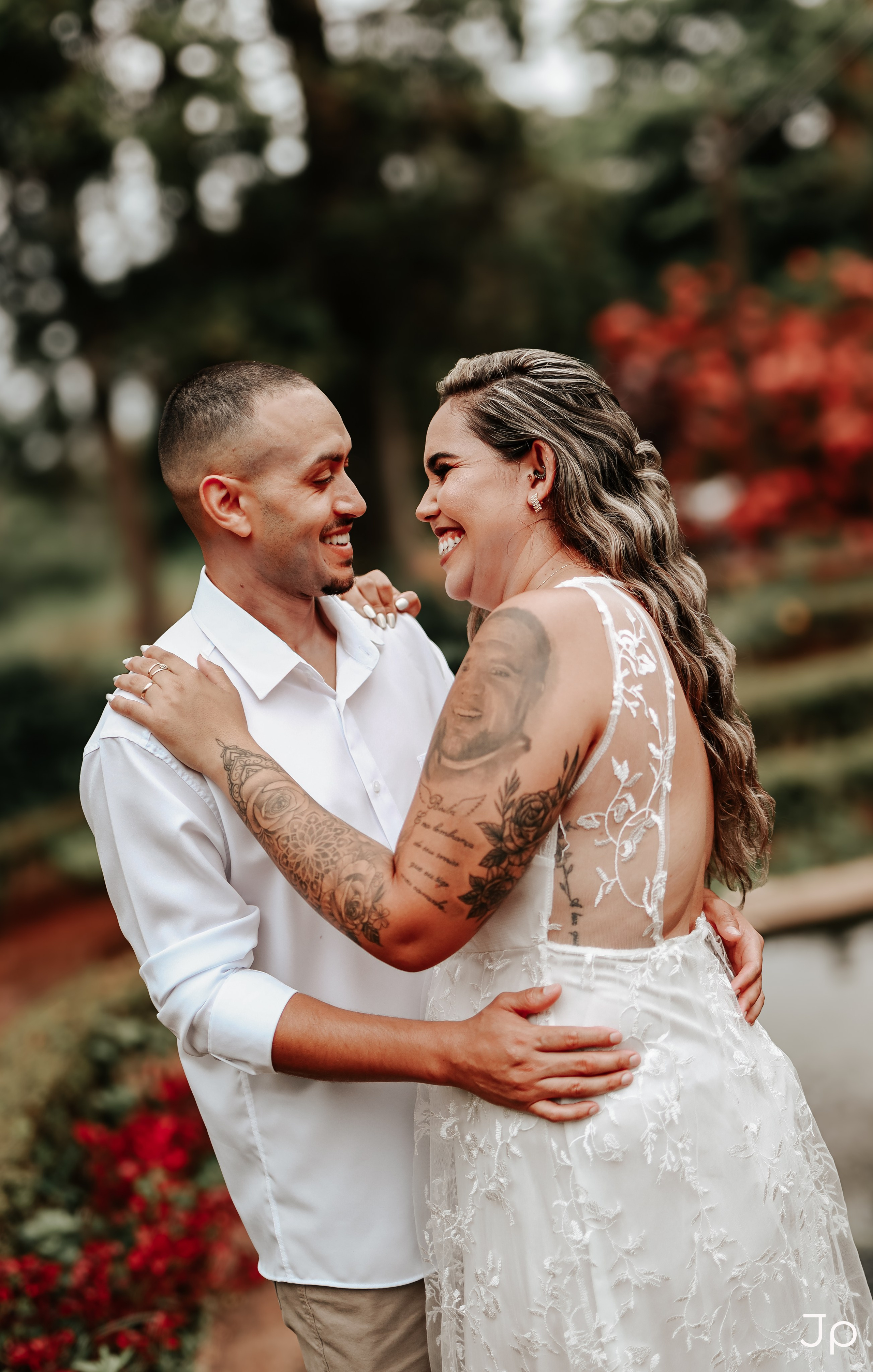 Ensaio pré-wedding ao ar livre com casal sorrindo entre plantas e caminhos de pedra, em Pederneiras.