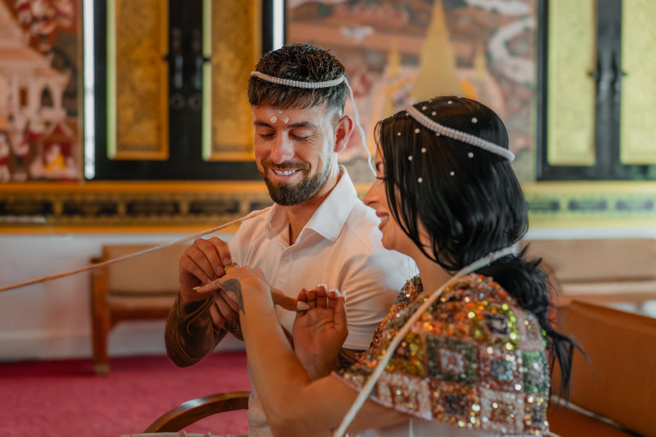 Bride and groom participating in a sacred Buddhist wedding blessing in Thailand