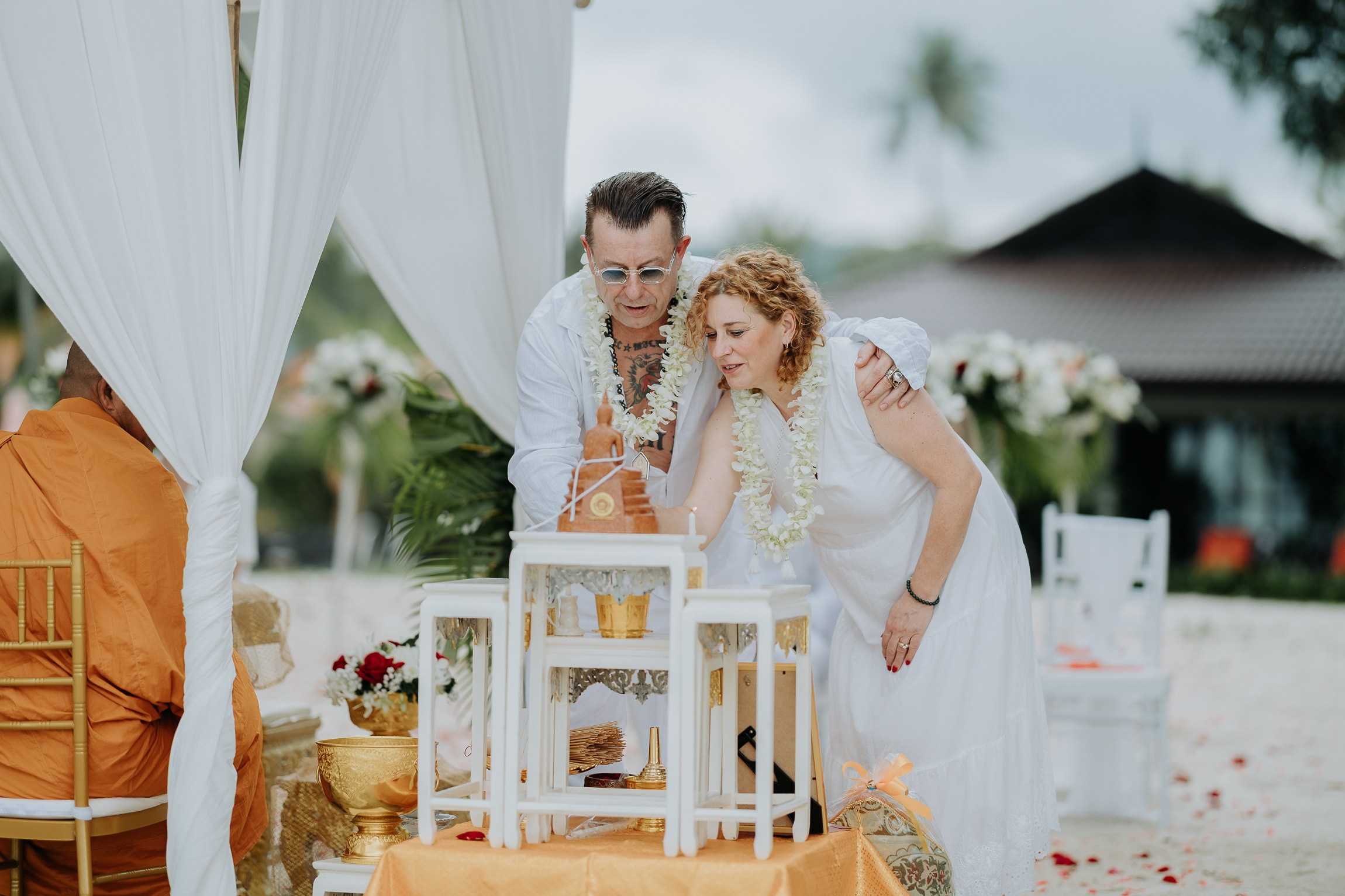 Bride and groom participating in a sacred Buddhist wedding blessing in Thailand