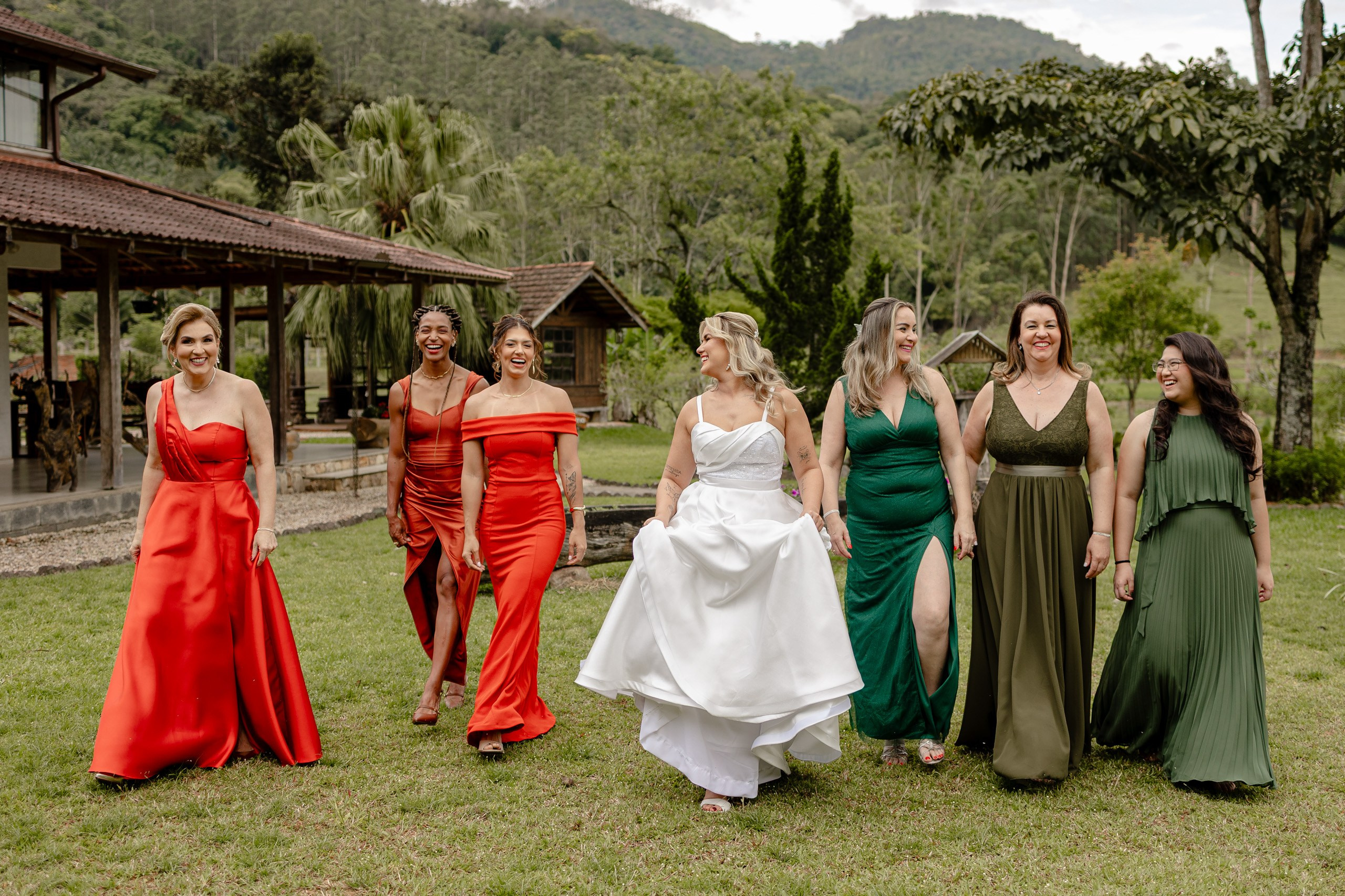 Fotógrafo de casamento em Santa Catarina; noiva e madrinhas caminhando juntas, sorridentes, vestidas com trajes coloridos em cenário natural ao ar livre.