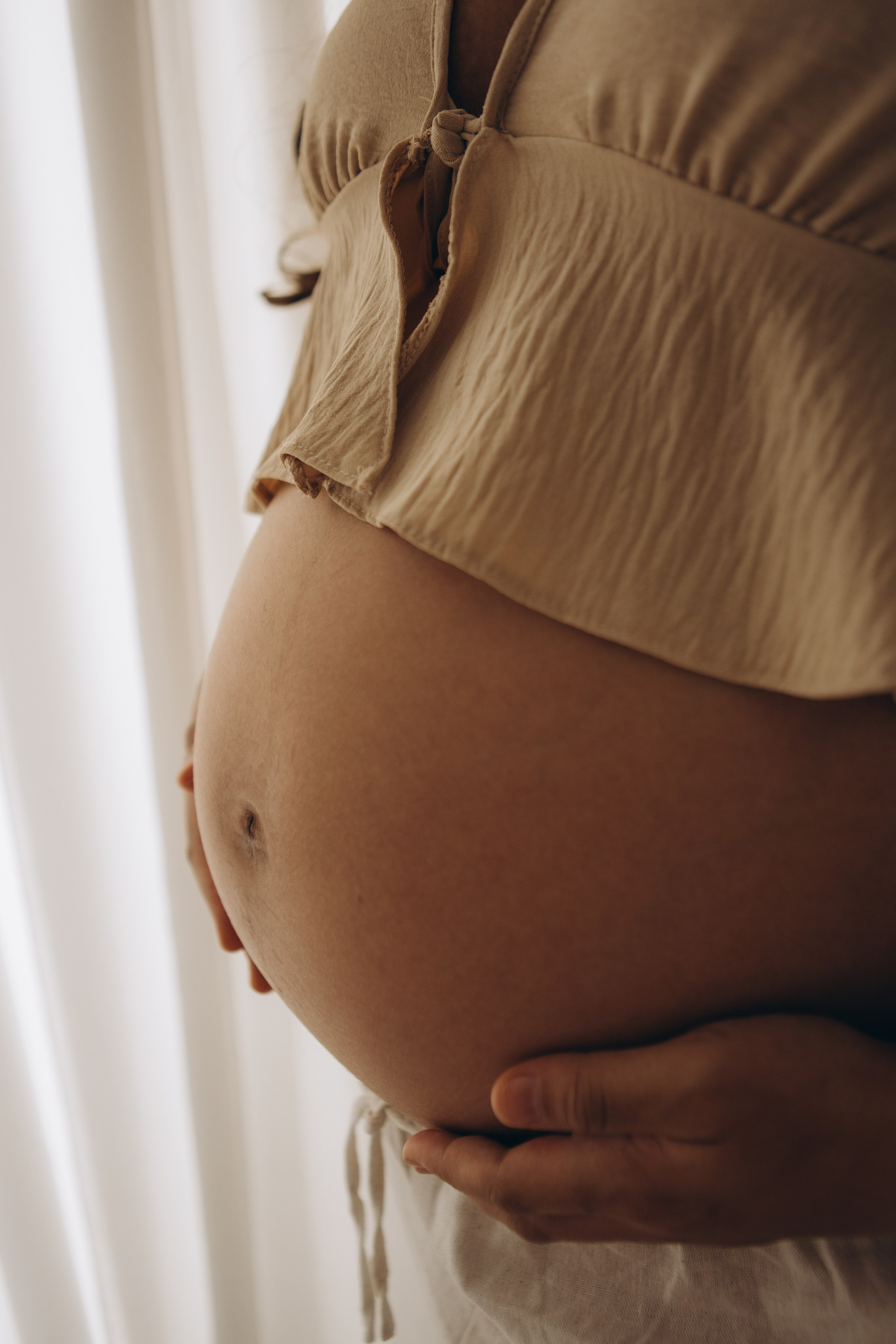detalhes da barriga da gestante com luz natural em estúdio em Sorocaba