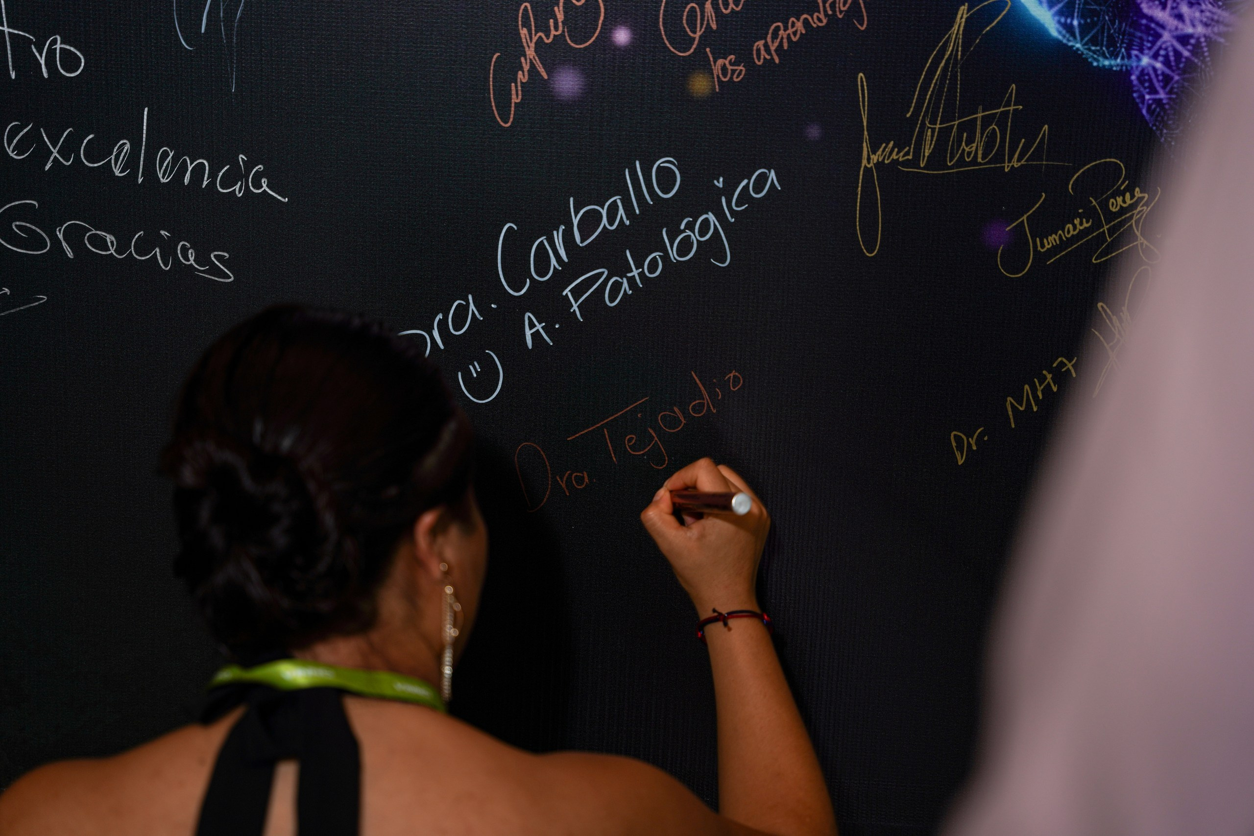 Signature on branded wall at corporate event with participant smiling.