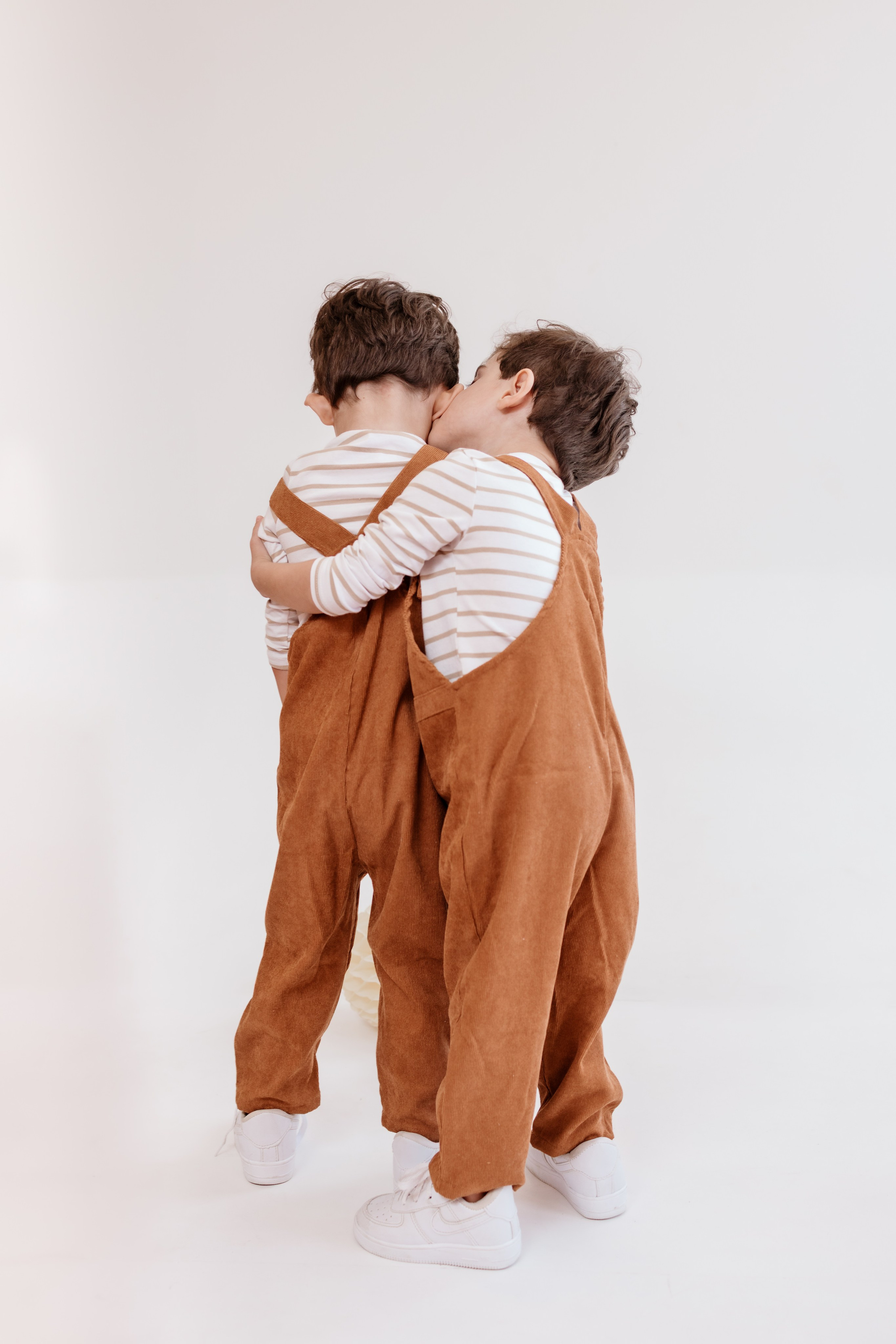 foto de irmãos gêmeos com 3 três dando um abraço, em estúdio