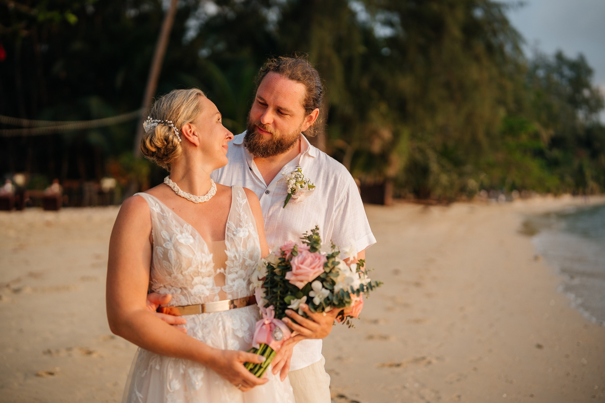 Bride and groom celebrating a beautiful beach wedding in Koh Samui, Thailand, surrounded by friends and family with tropical ocean views