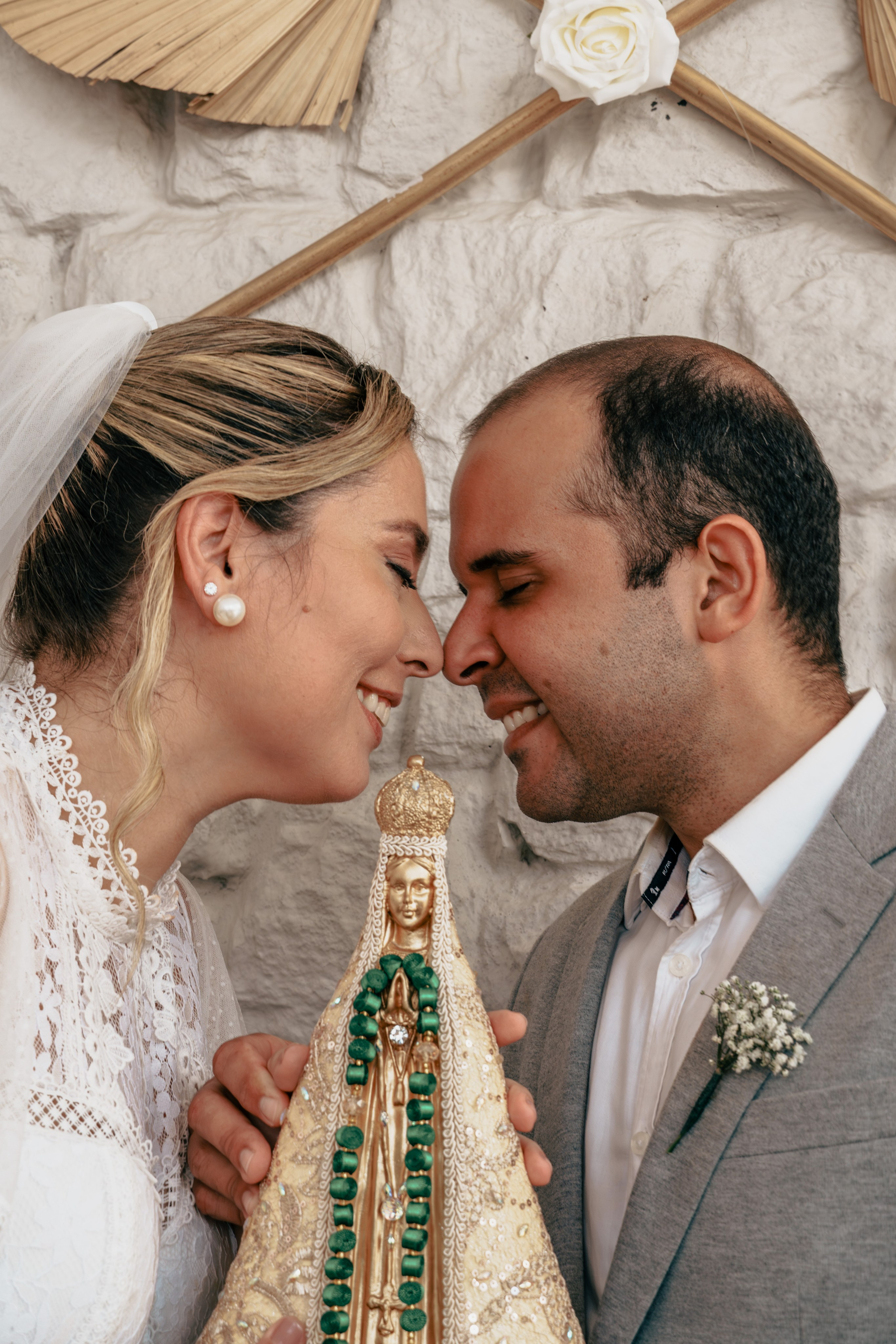 Noivos próximos durante cerimônia religiosa do casamento com imagem de Nossa Senhora