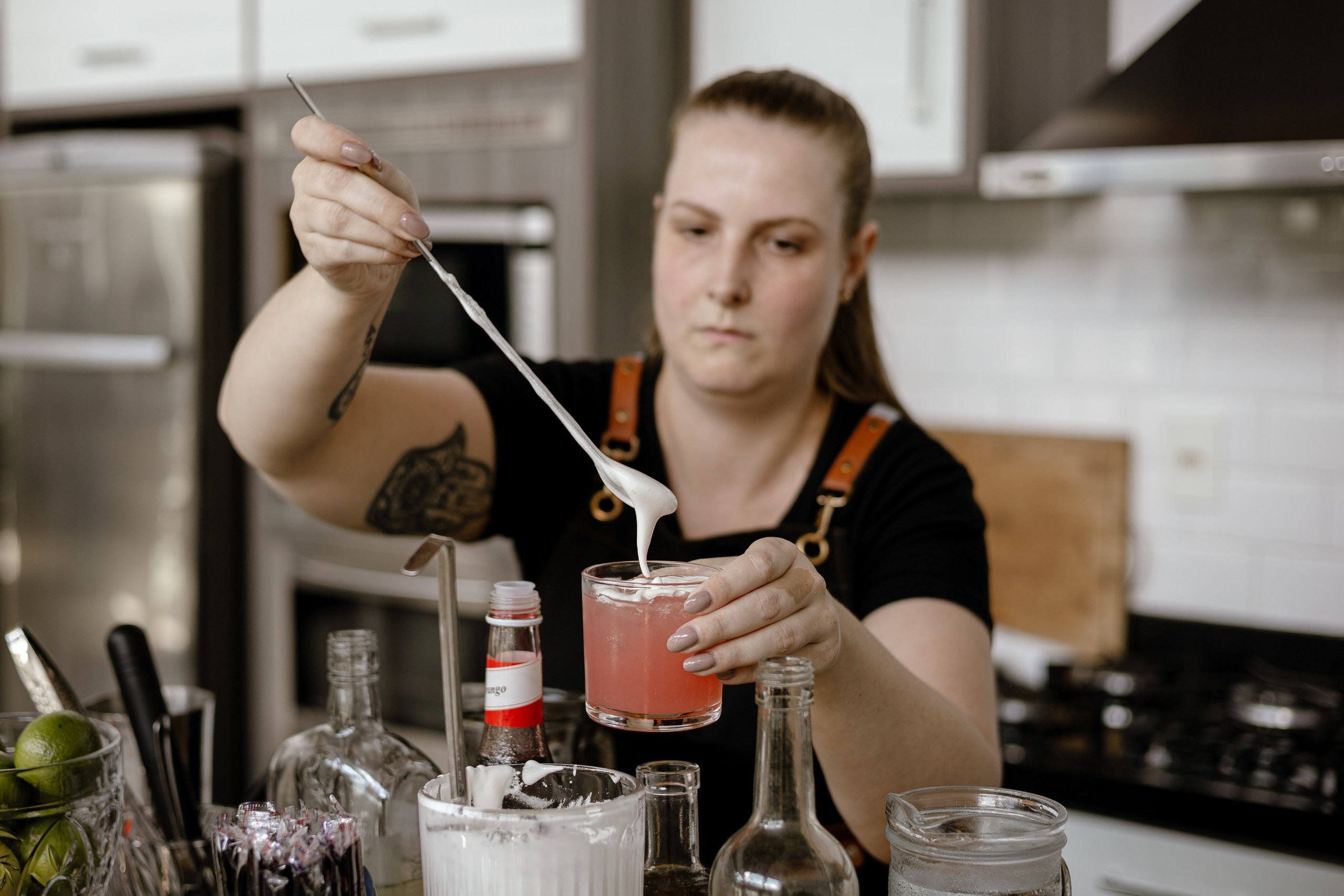 Fotografia de cobertura de festa e evento em Itajaí mostrando uma bartender preparando um drink colorido com espuma em um bar.