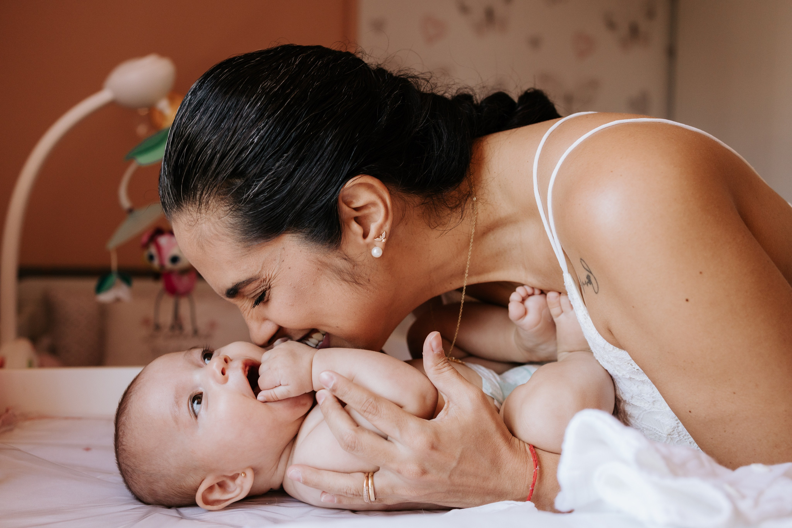 momento espontâneo de mãe e filha, no quartinho de bebê, durante a troca de fralda