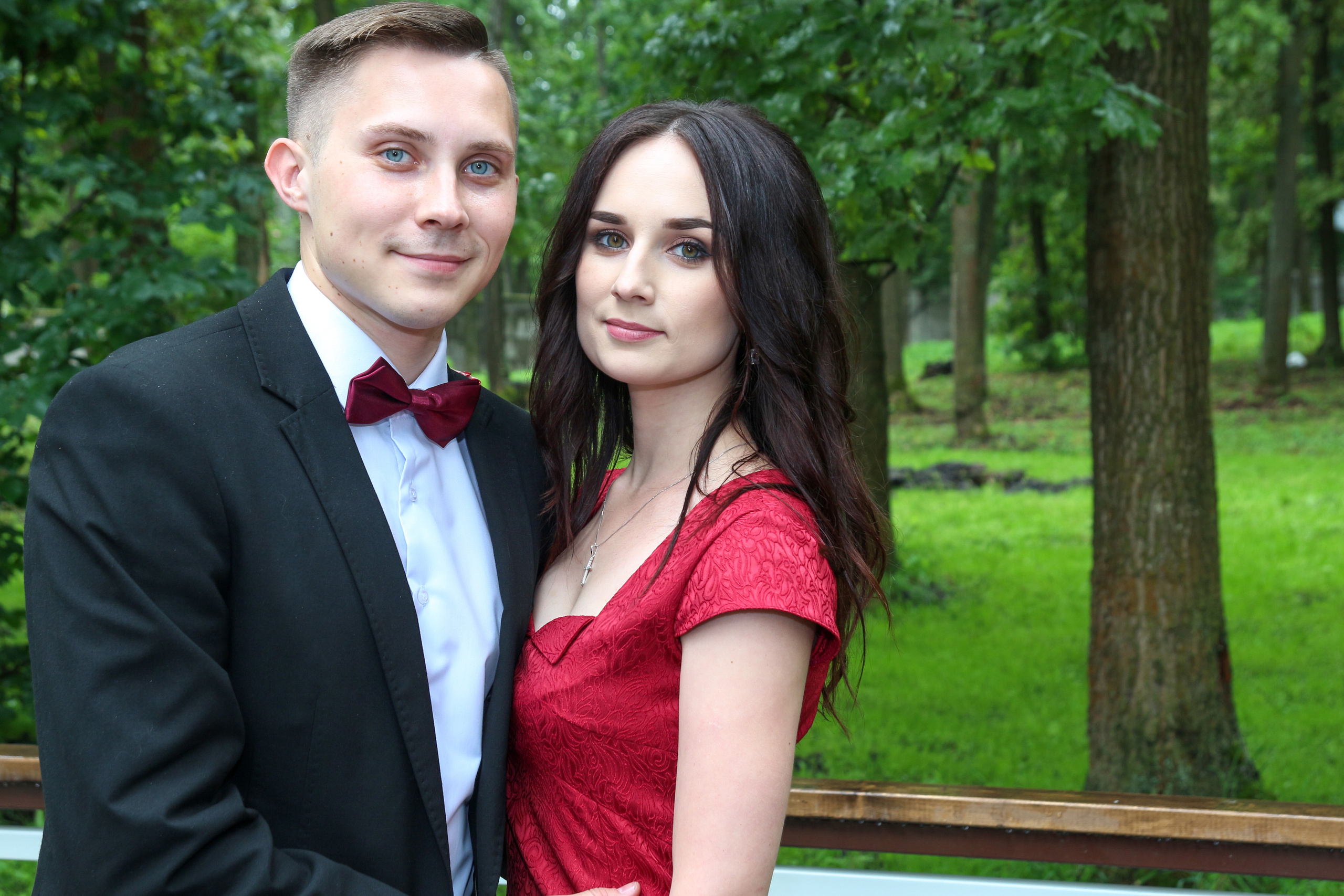 Elegant couple portrait with a woman in a red dress, outdoor anniversary session.