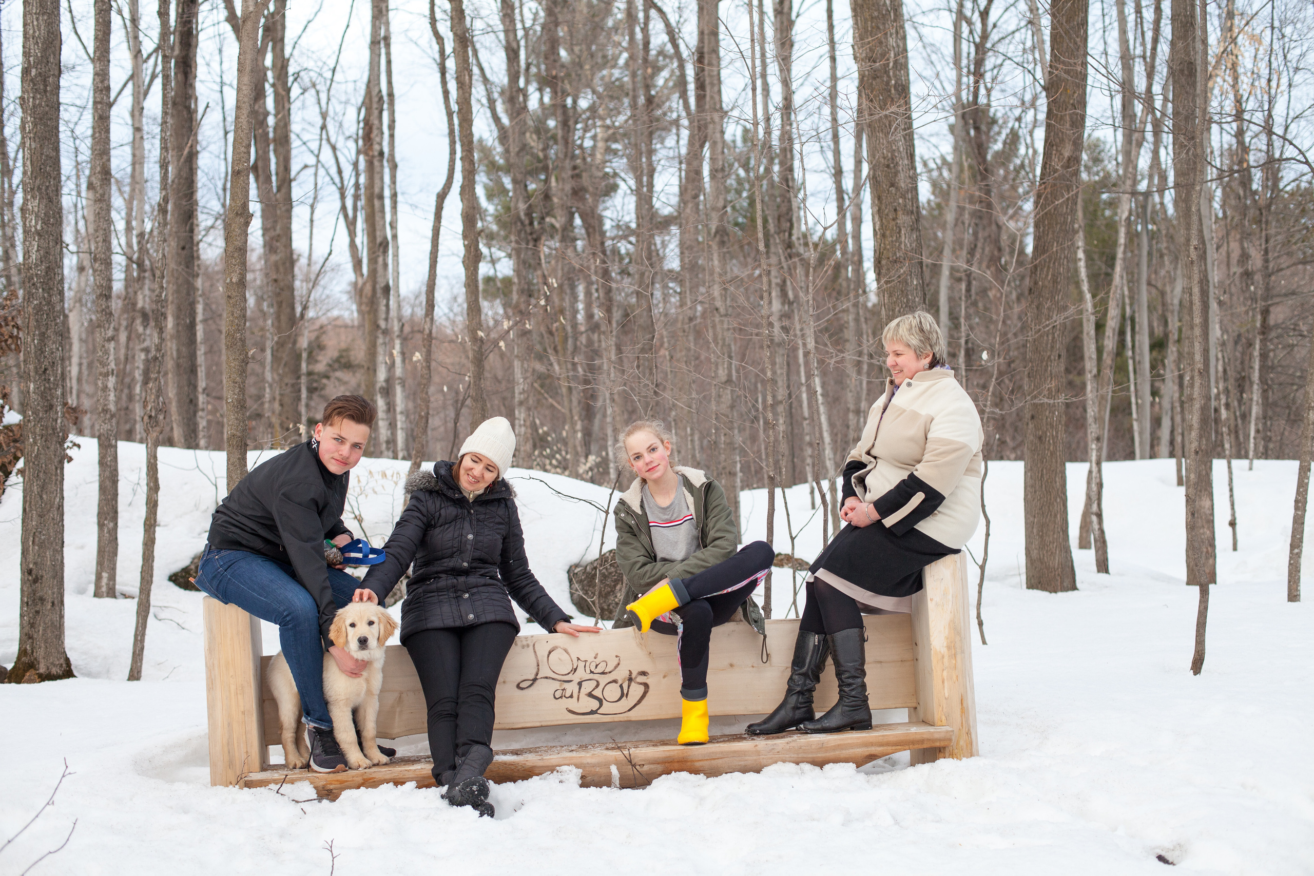 Extended family portrait with a dog on a snowy bench, winter forest, Ontario.