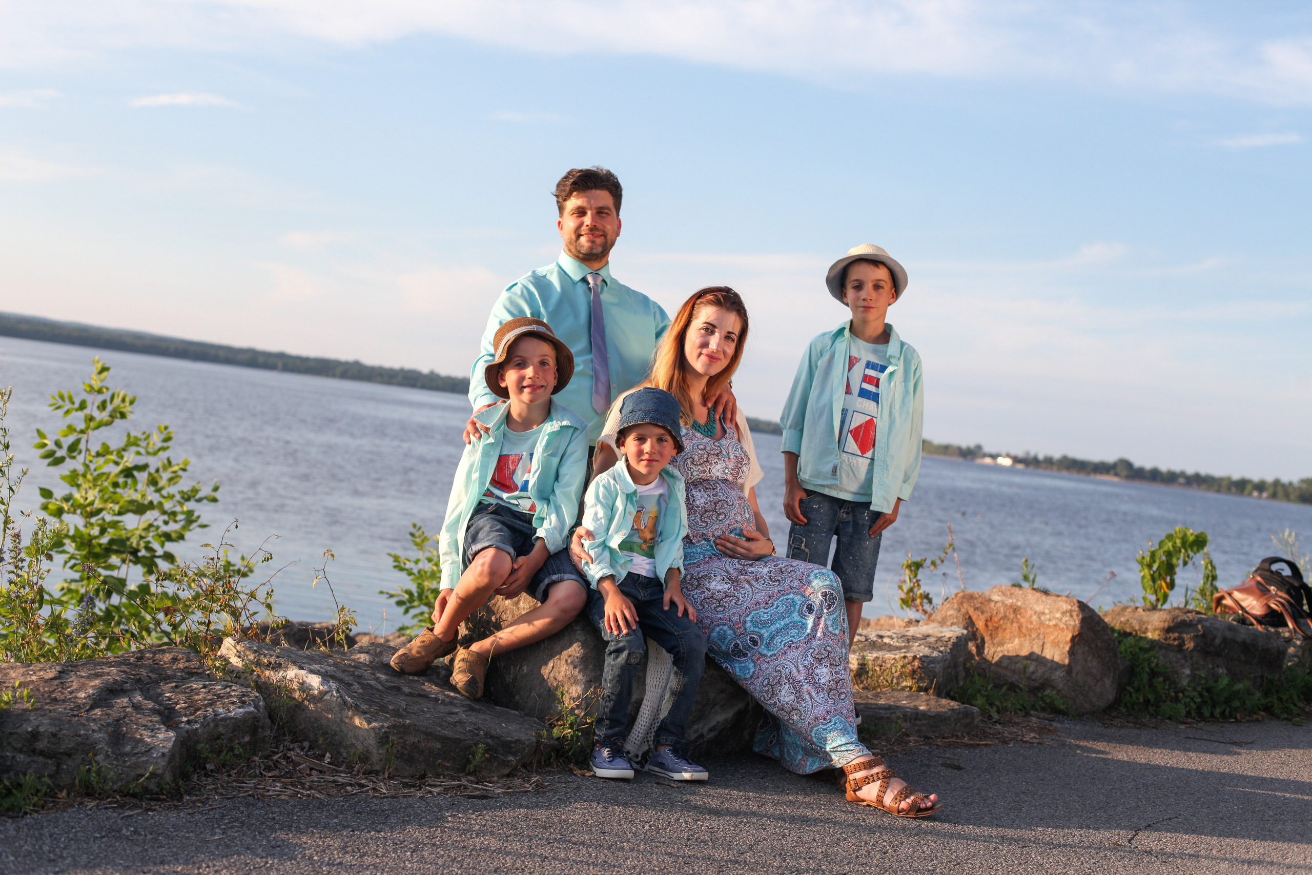 Large family group portrait sitting on the rocks by the lakeside, Eastern Ontario. Maternity family photo session on the rocks by the lake, Eastern Ontario.
