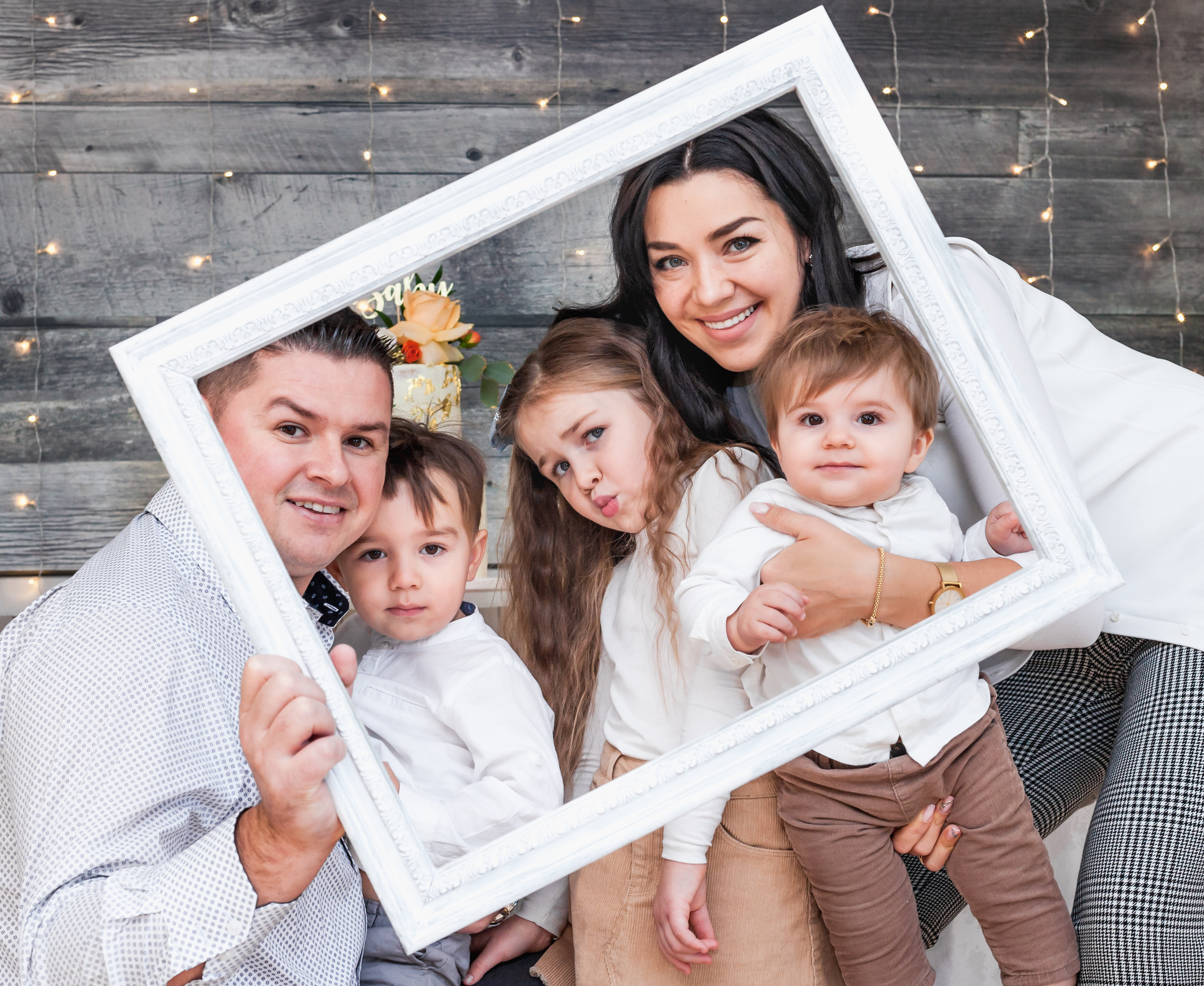 Fun family portrait holding a large white photo frame prop, creative session.