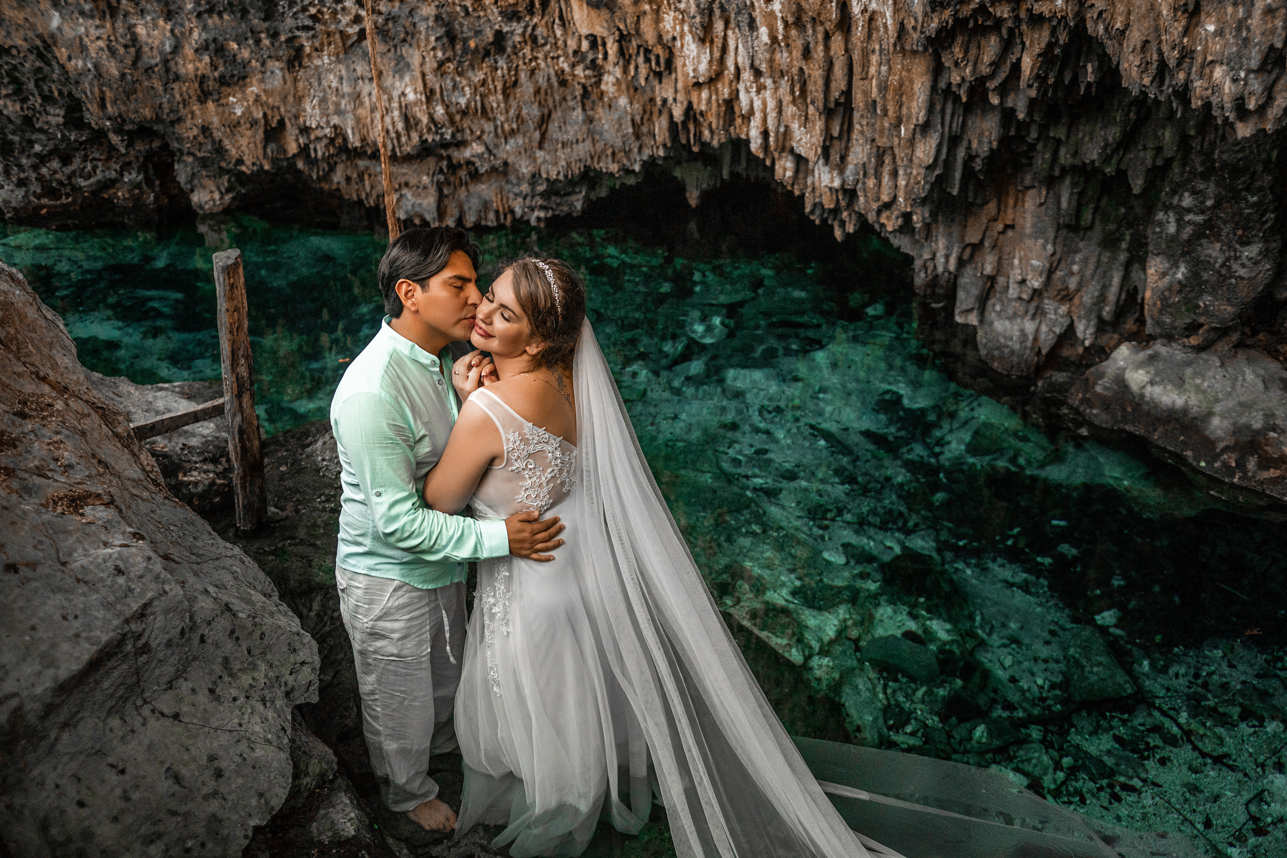 Couple in wedding attire at turquoise cenote in Playa del Carmen