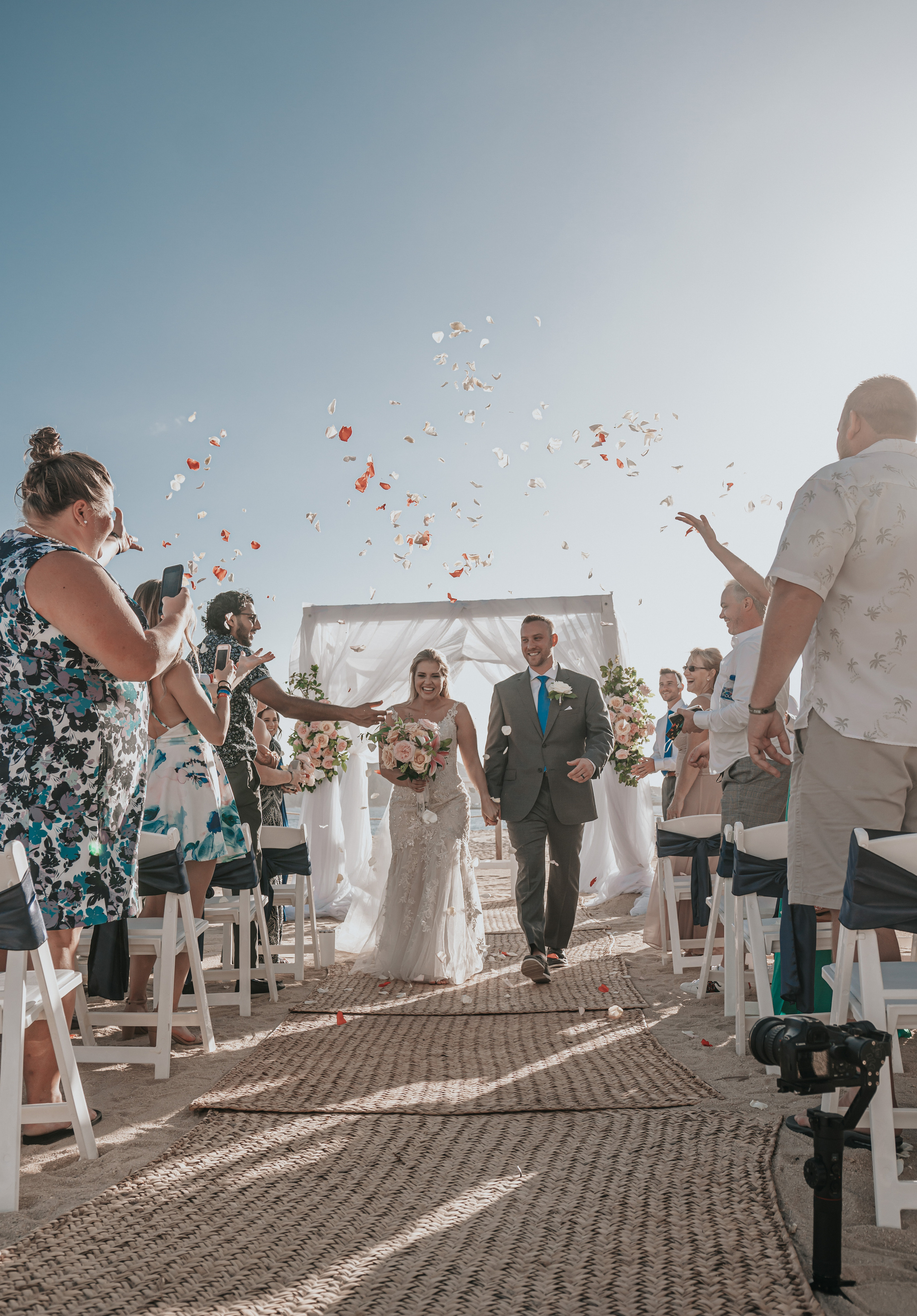 Bride and groom under wedding arch near Pacific Ocean