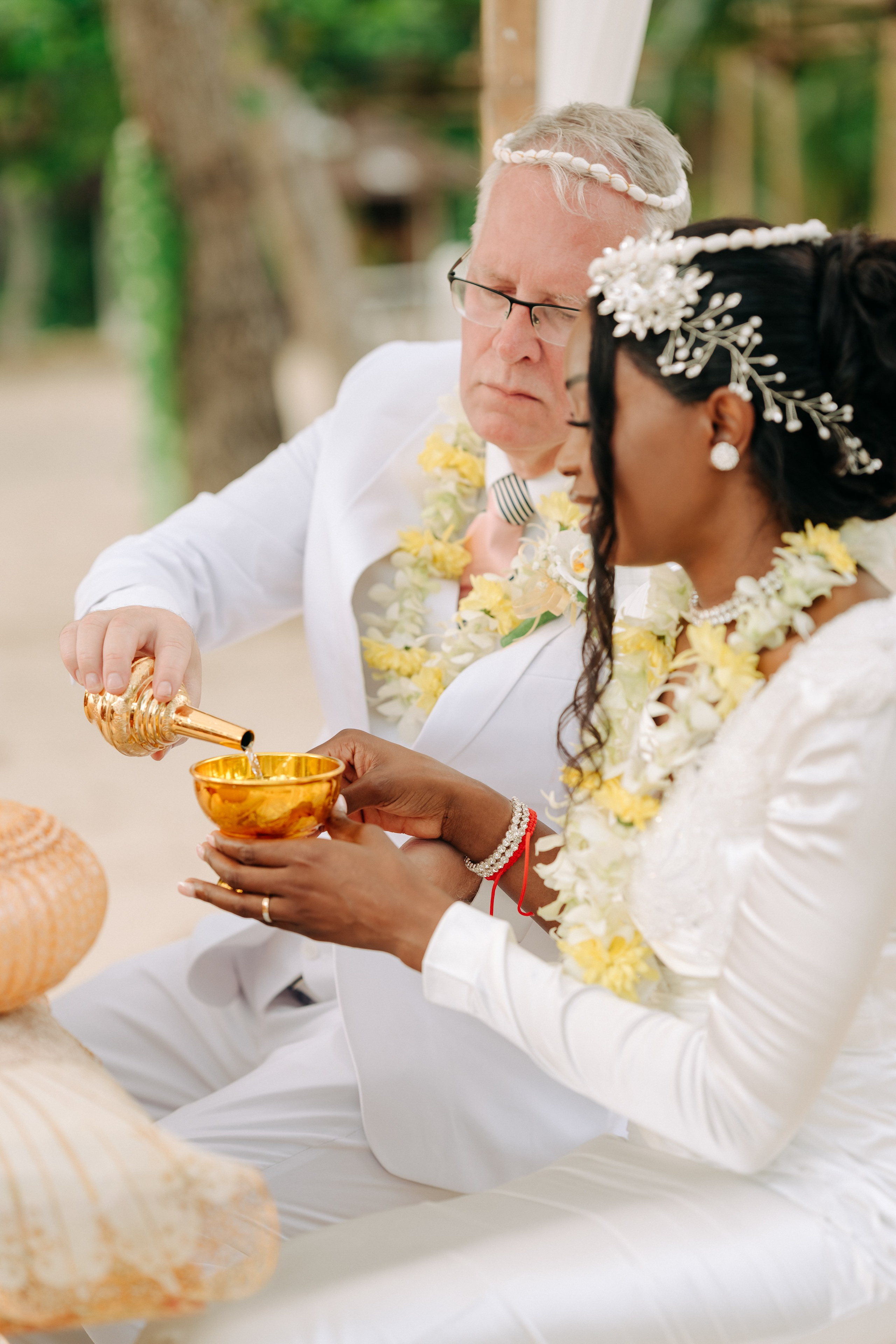 Newlywed couple celebrating a Buddhist wedding ceremony on a beautiful beach in Koh Samui, Thailand.