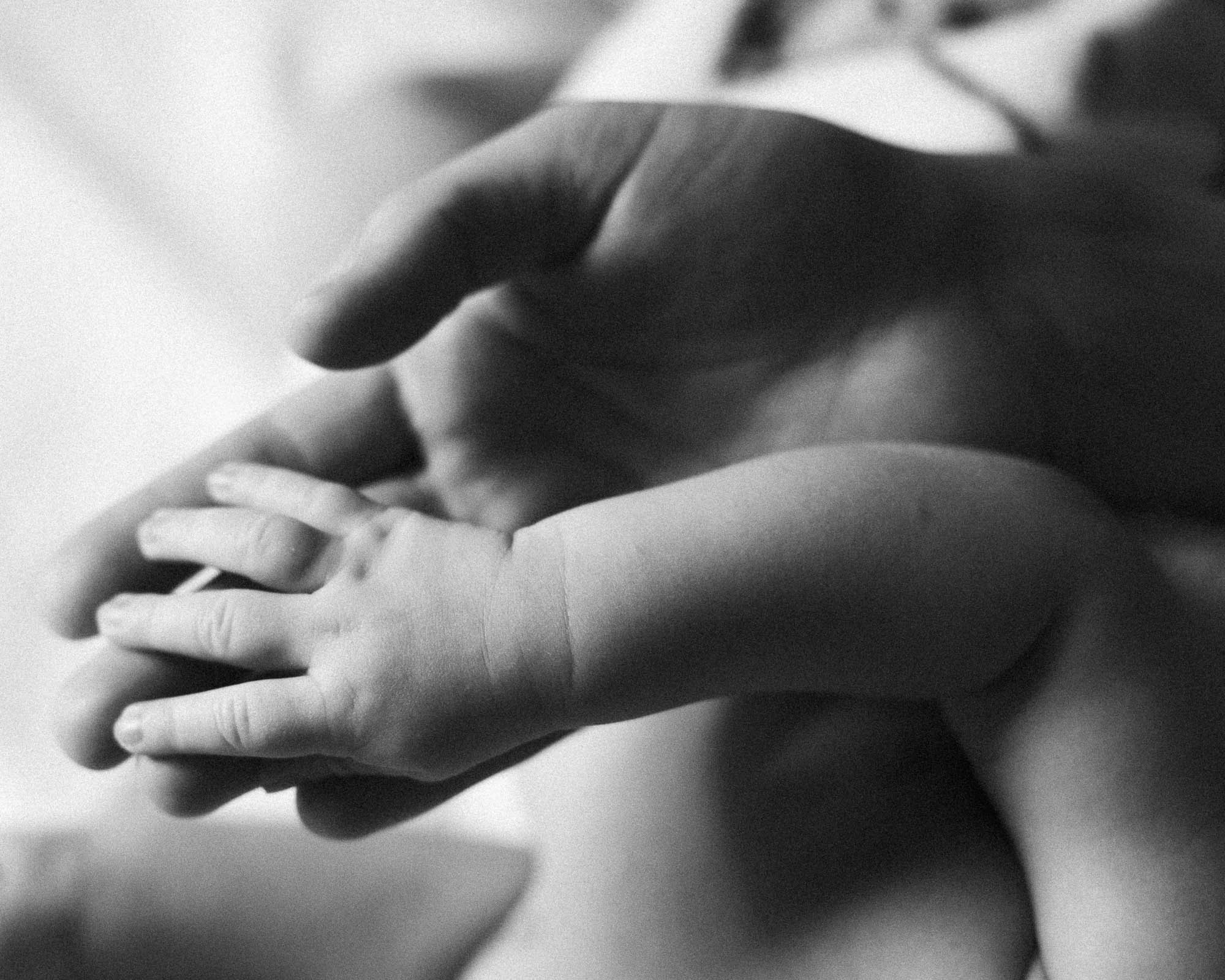 Petites mains d’un nouveau-né dans celles de ses parents